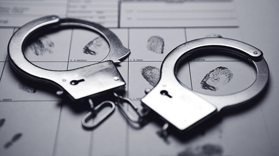 Handcuffs on top of a fingerprint form are shown in this file photo. (Credit: Blake David Taylor/Thinkstock)