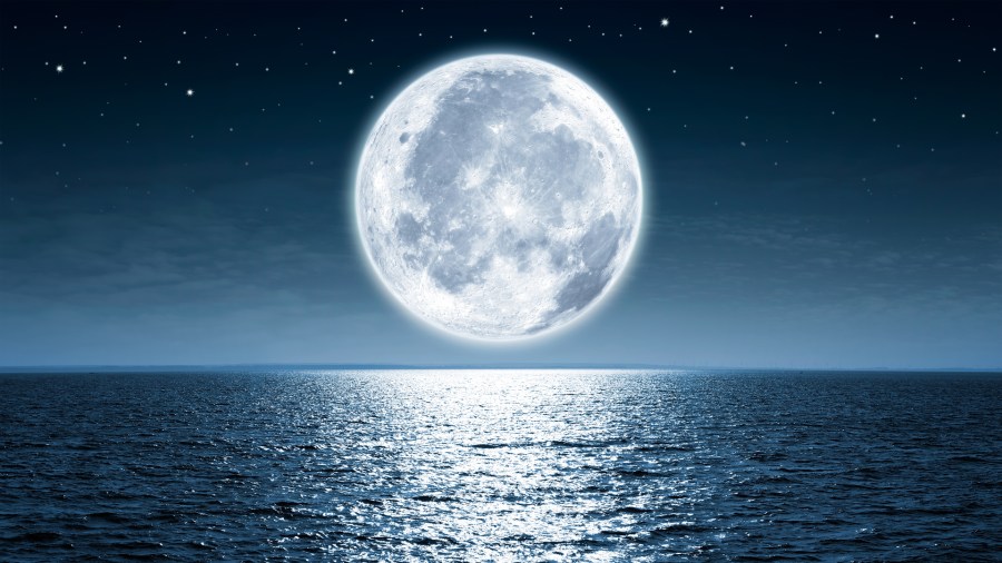 Full moon rising over empty ocean at night. (Credit: iStock / Getty Images Plus)