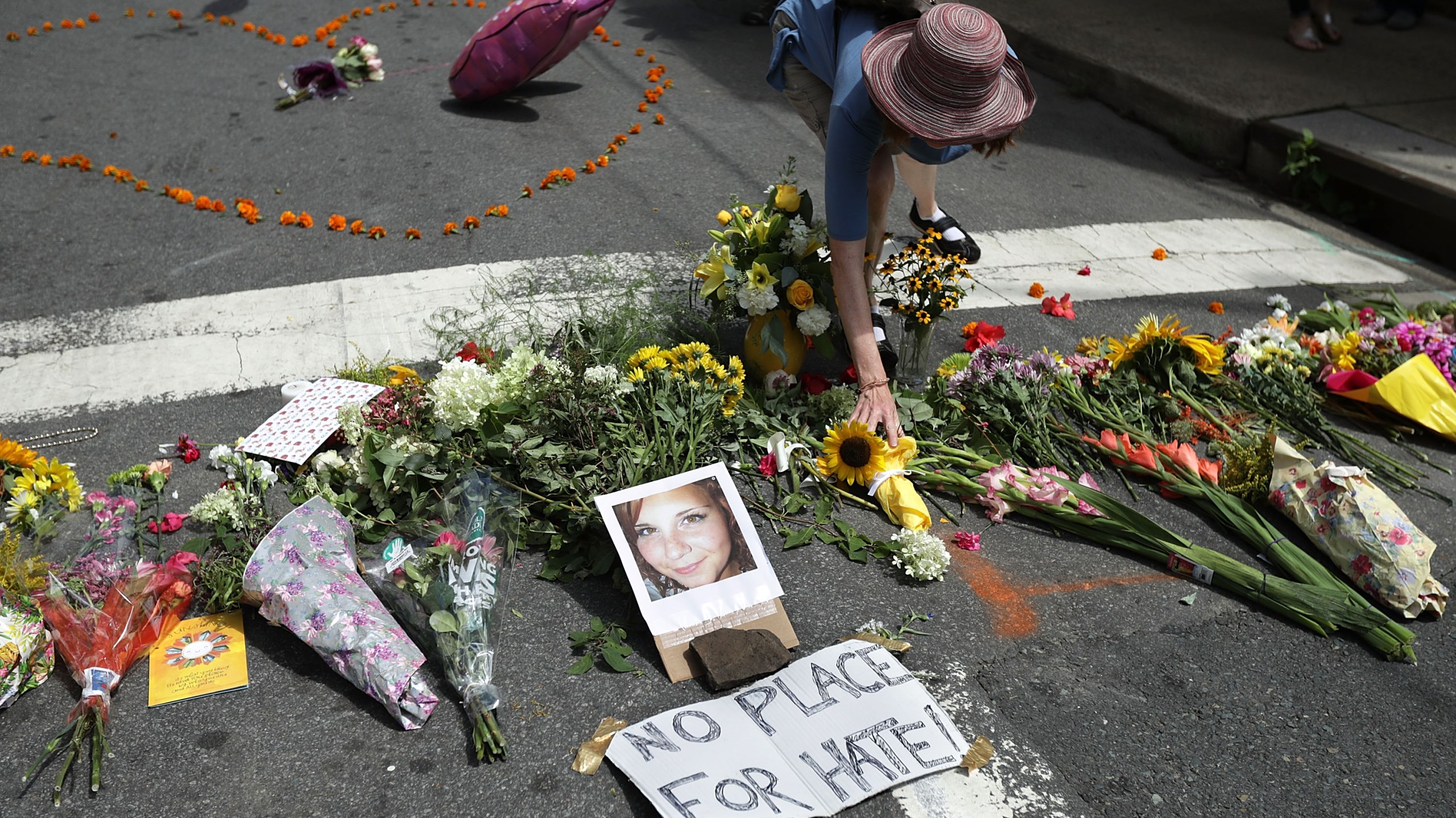 A woman places flowers at an informal memorial to 32-year-old Heather Heyer, who was killed when a car plowed into a crowd of people protesting against the white supremacist Unite the Right rally, August 13, 2017 in Charlottesville, Virginia. (Credit: Chip Somodevilla/Getty Images)