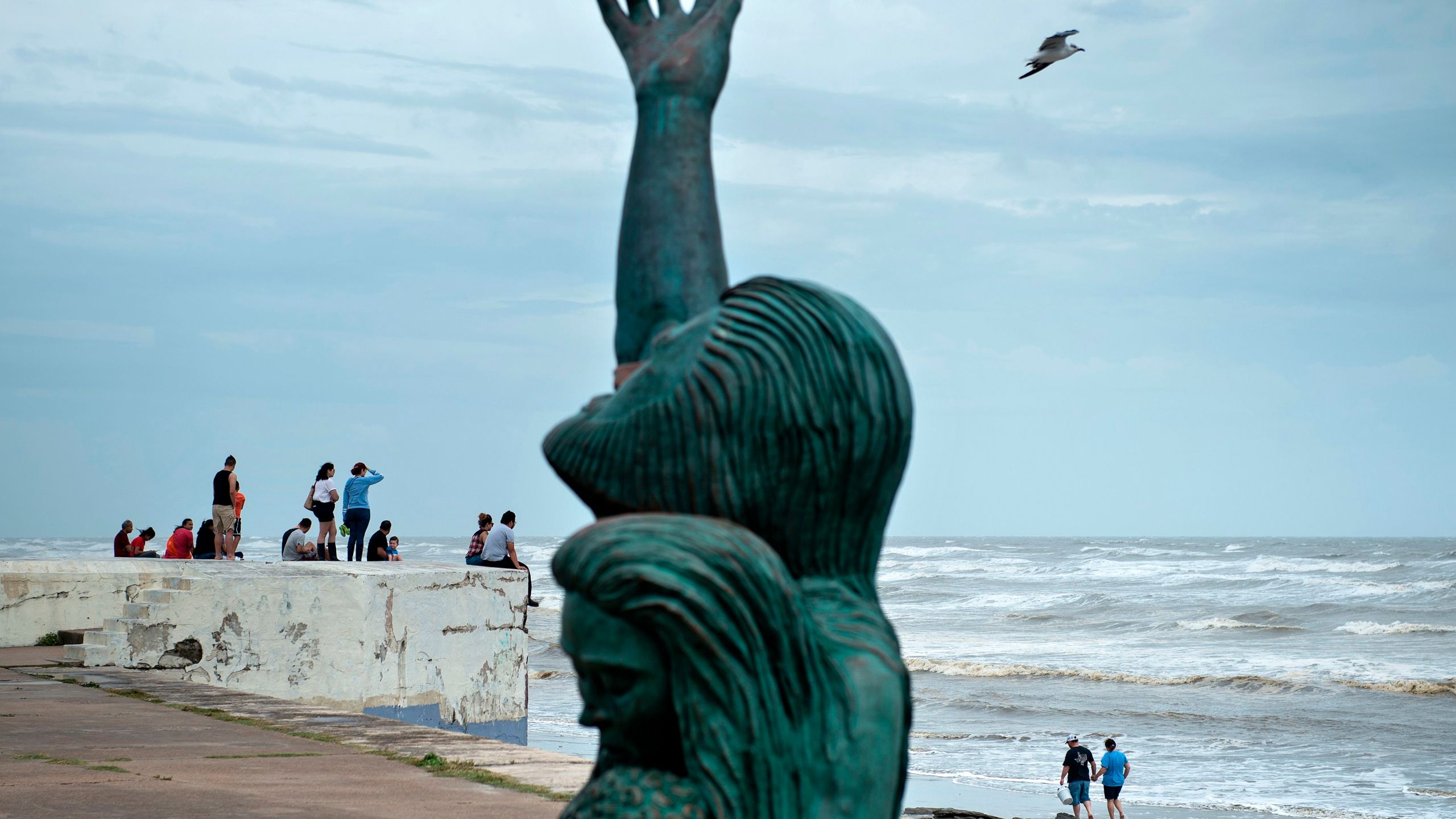 People look out from a seawall to the Gulf of Mexico as the effects of Hurricane Harvey are seen Aug. 26, 2017, in Galveston, Texas. (Credit: Brendan Smialowski / AFP / Getty Images)