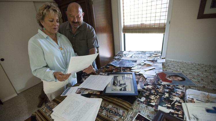 Sharon Holland, left, and husband Carty look over photos and letters written by their son Andrew Holland. (Credit: Brian van der Brug / Los Angeles Times)