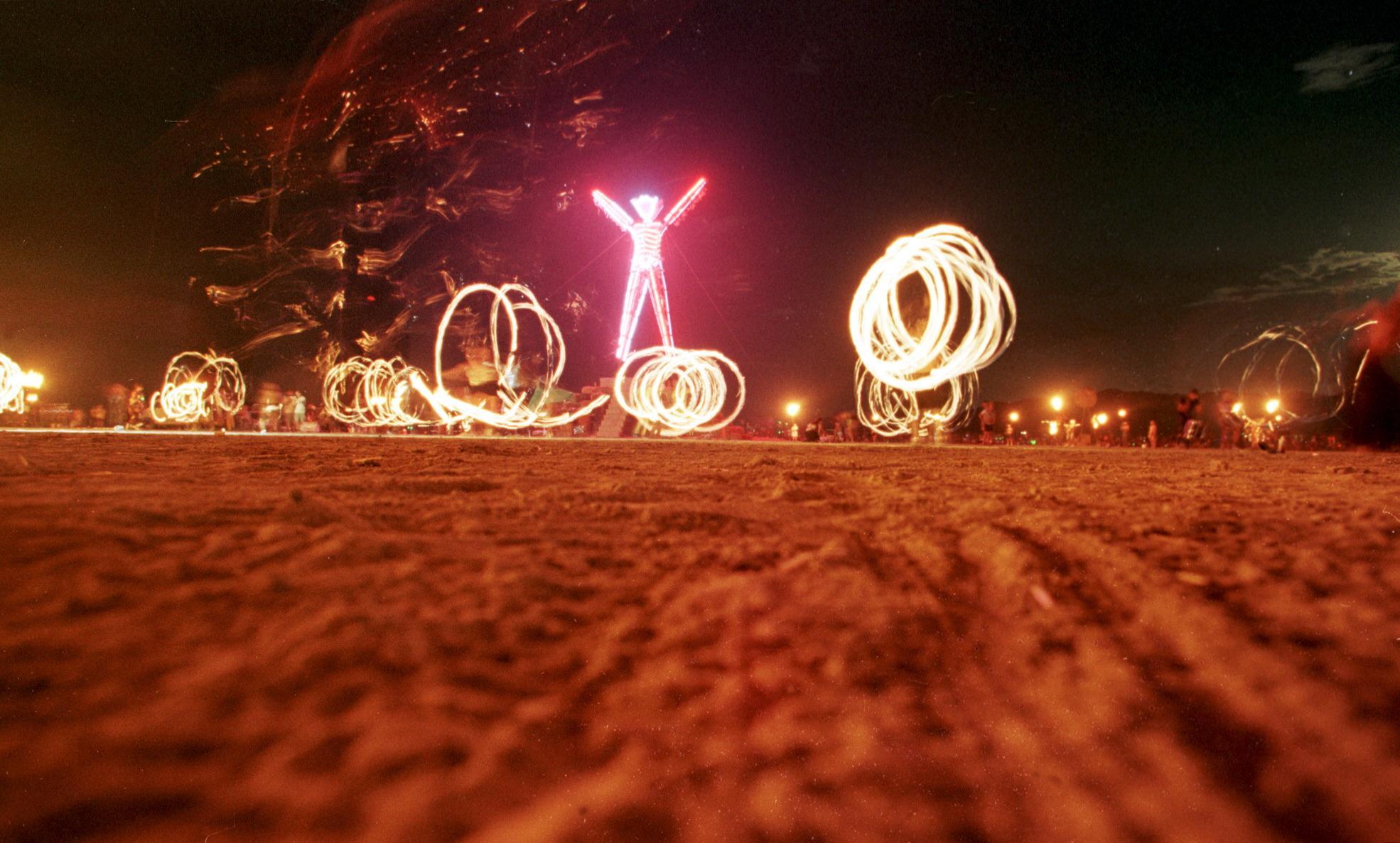 Dancers at the "Burning Man" festival create patterns with fireworks in the Black Rock Desert of Nevada just prior to burning a five-story, neon-lit effigy of a man on the last night of the week-long festival on Sept. 6, 1998. (Credit: Mike Nelson / AFP / Getty Images)