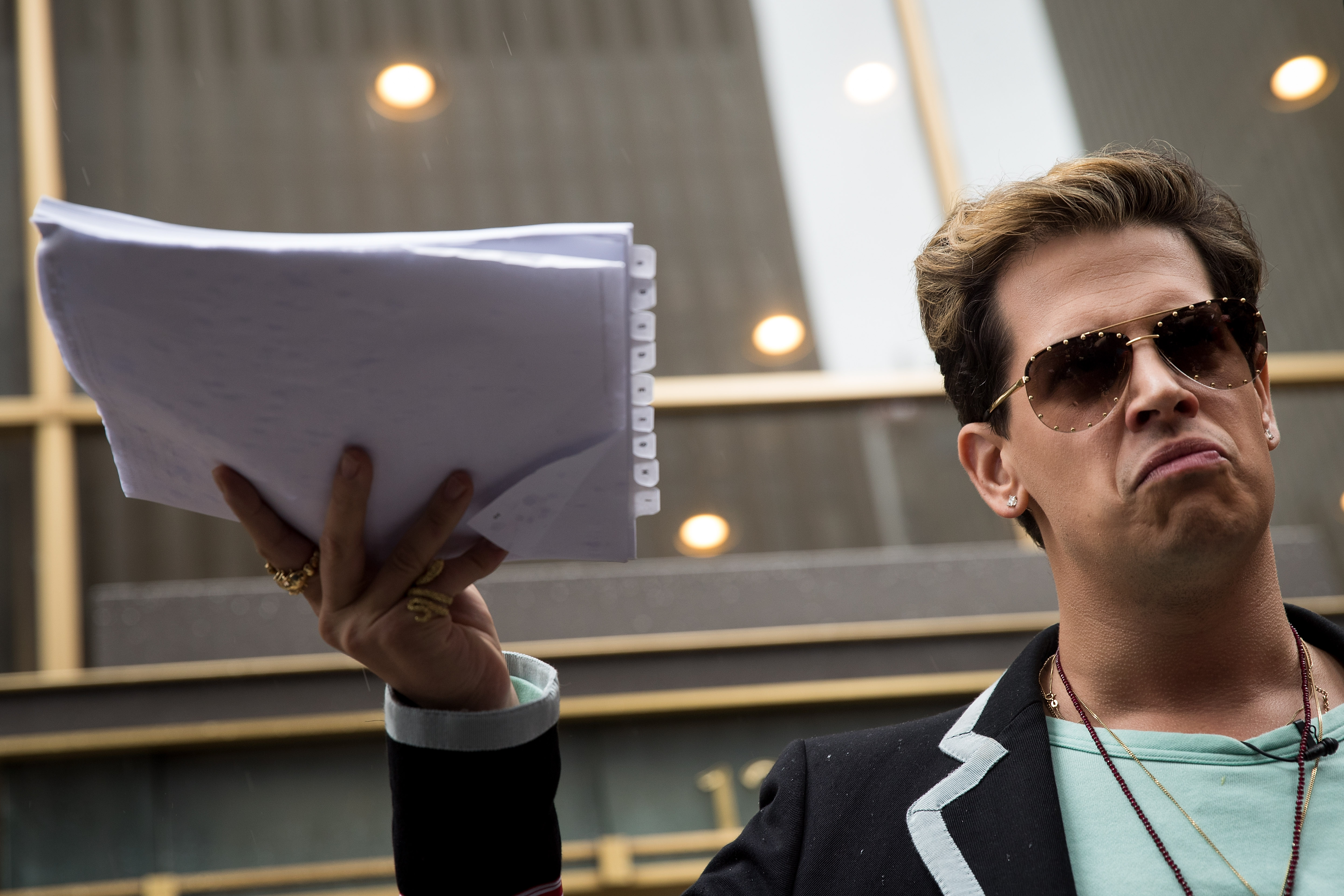 Milo Yiannopoulos holds up a copy of a legal complaint as he speaks outside the offices of Simon & Schuster publishing company after it canceled his book deal, July 7, 2017, in New York City. (Credit: Drew Angerer/Getty Images)