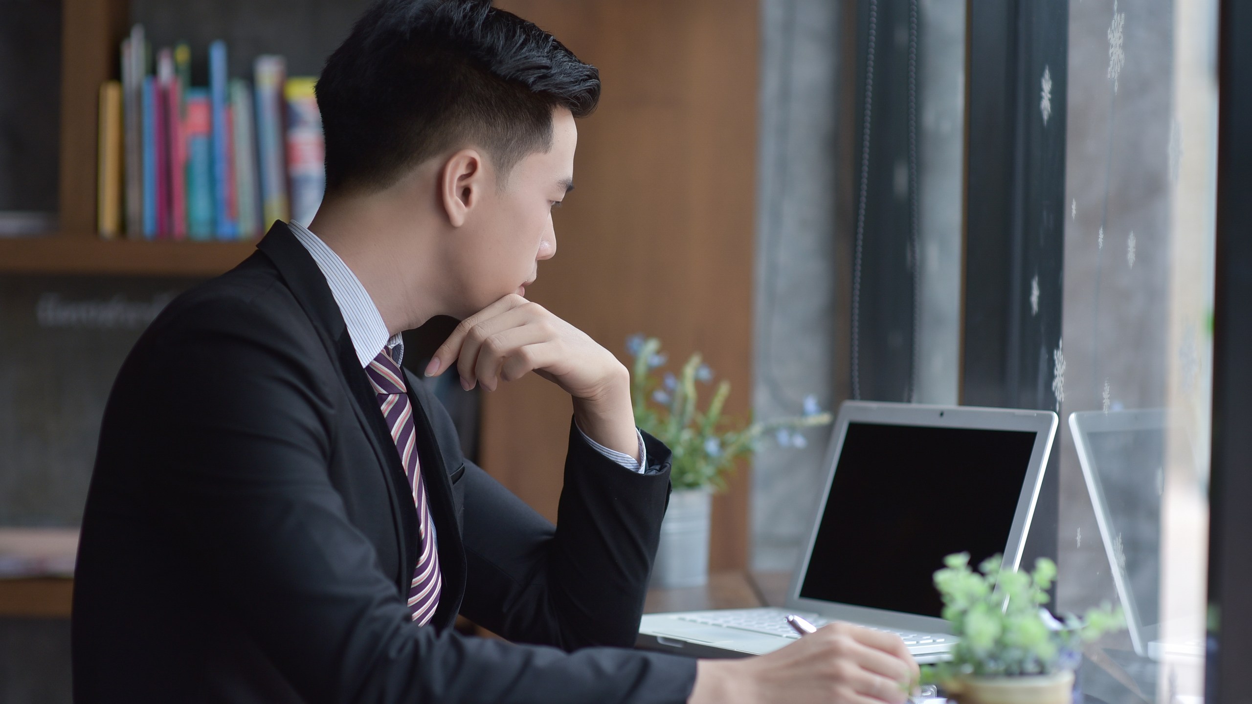 A young business man is seen sitting at his desk in this file photo. (Credit: iStock / Getty Images Plus)