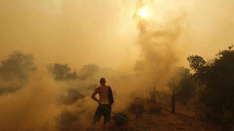 Sunland resident Jeff Dalton sprays water near his home as flames from the La Tuna fire approach. (Credit: Genaro Molina / Los Angeles Times)