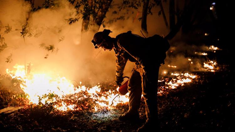 Firefighter Brandon Tolp works to prevent flames from crossing Highway 29, north of Calistoga, Calif. as wildfires raged in Northern California in October, 2017. (Credit: Marcus Yam / Los Angeles Times)