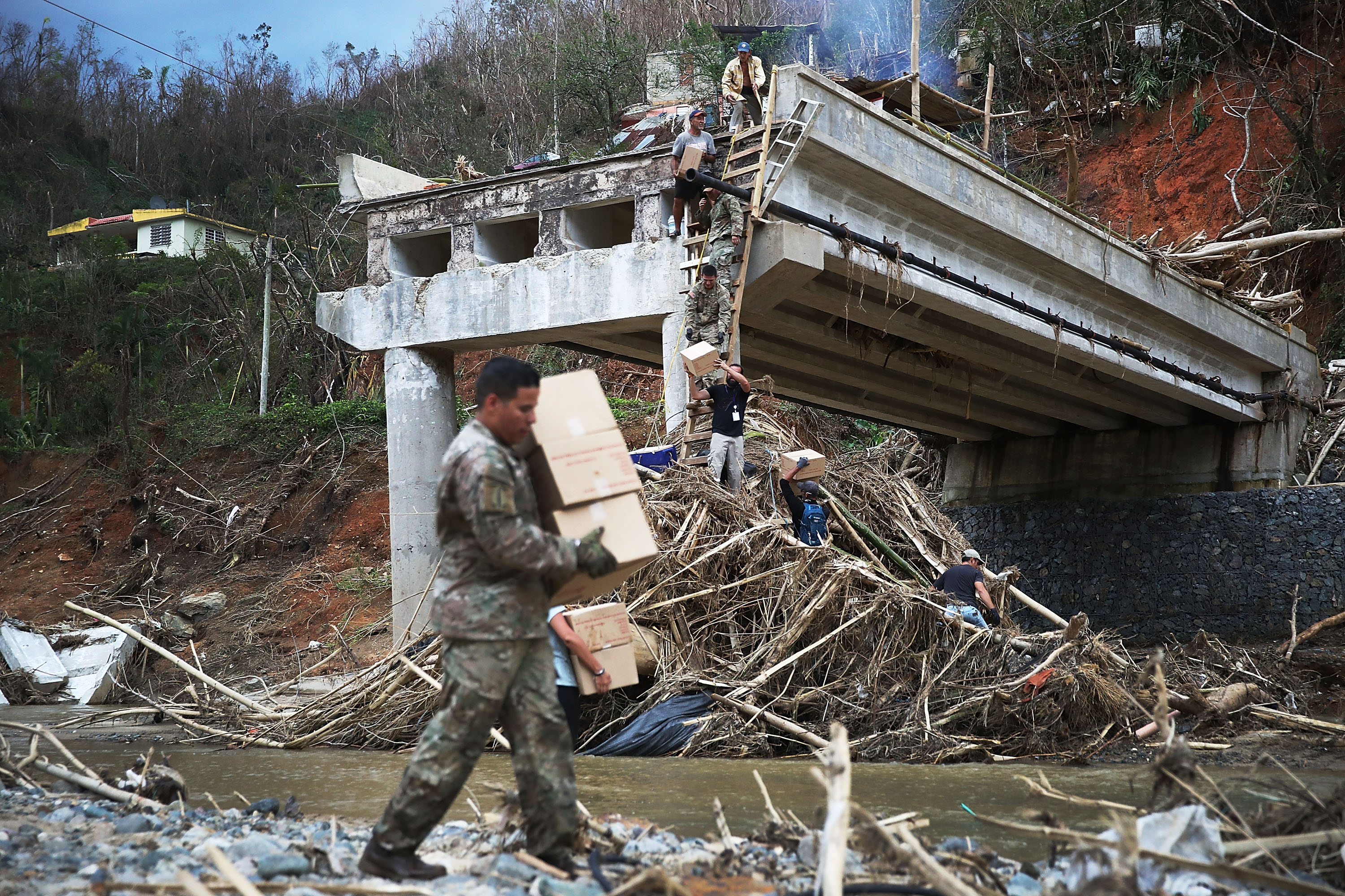 Members of the U.S. Army deliver boxes up a makeshift ladder to people that were cut off after a bridge collapsed when Hurricane Maria swept through Puerto Rico, Oct. 5, 2017, in the town of Utuado. (Credit: Joe Raedle / Getty Images)