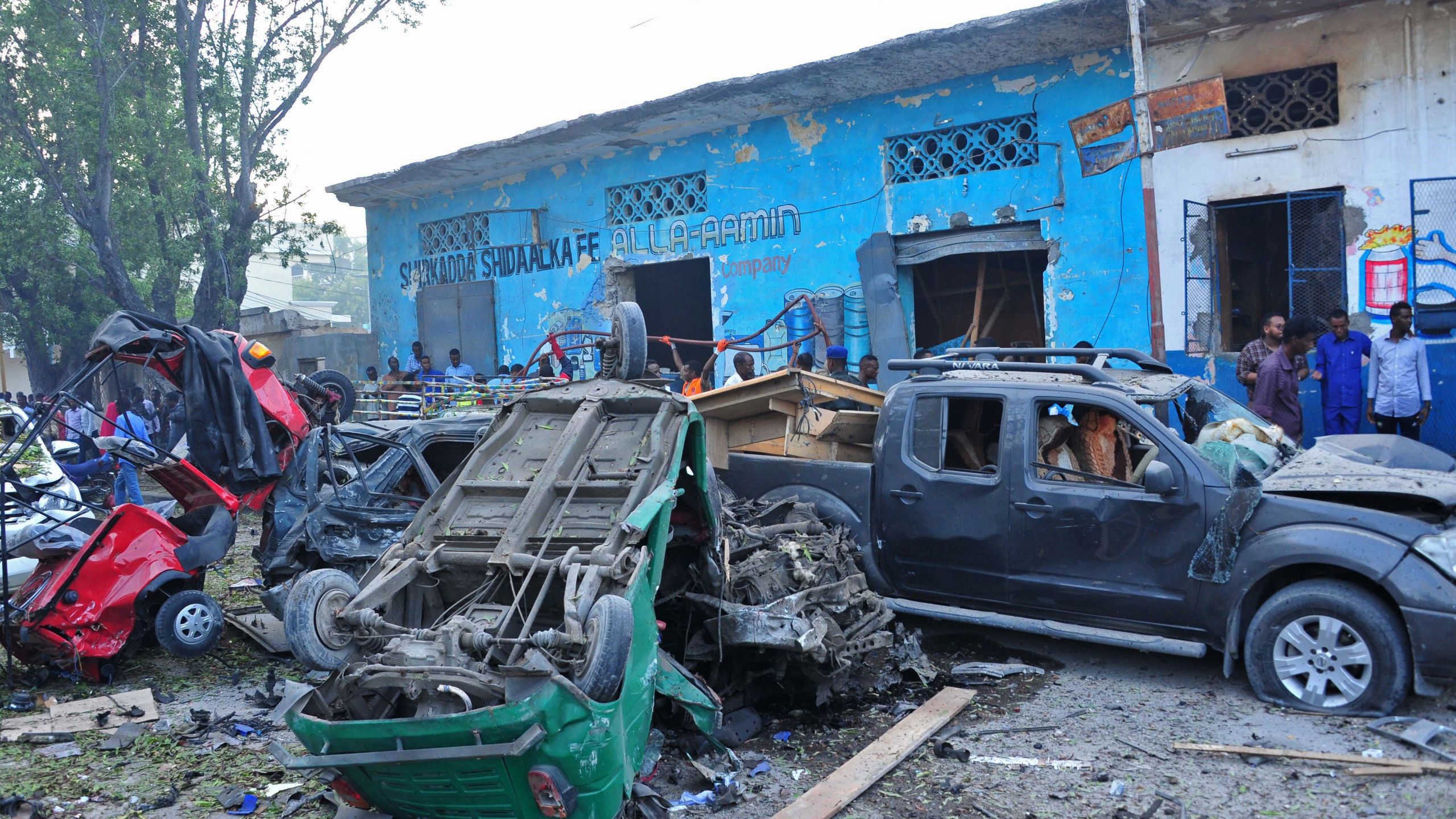 People stand among damages at the scene of a blast after two car bombs exploded in Mogadishu on October 28, 2017. (Credit: MOHAMED ABDIWAHAB/AFP/Getty Images)