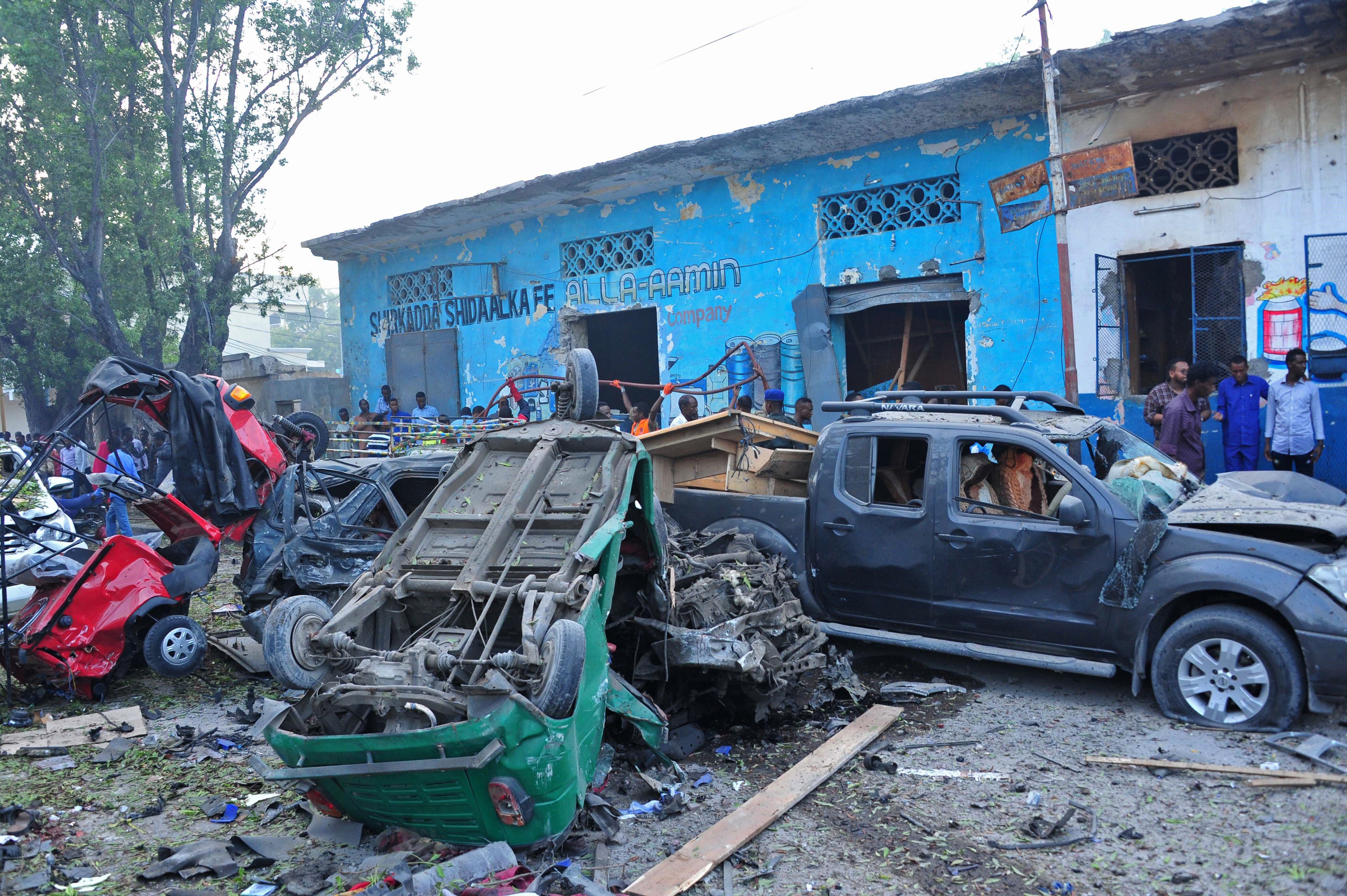 People stand among damages at the scene of a blast after two car bombs exploded in Mogadishu on October 28, 2017. (Credit: MOHAMED ABDIWAHAB/AFP/Getty Images)