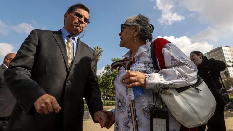 Calif. Atty. Gen. Xavier Becerra, left, speaks to Martha Wilson, a customer of electronics retailer Curacao, before a news conference Friday in Los Angeles to announce a civil suit against Curacao. (Credit: Irfan Khan / Los Angeles Times)