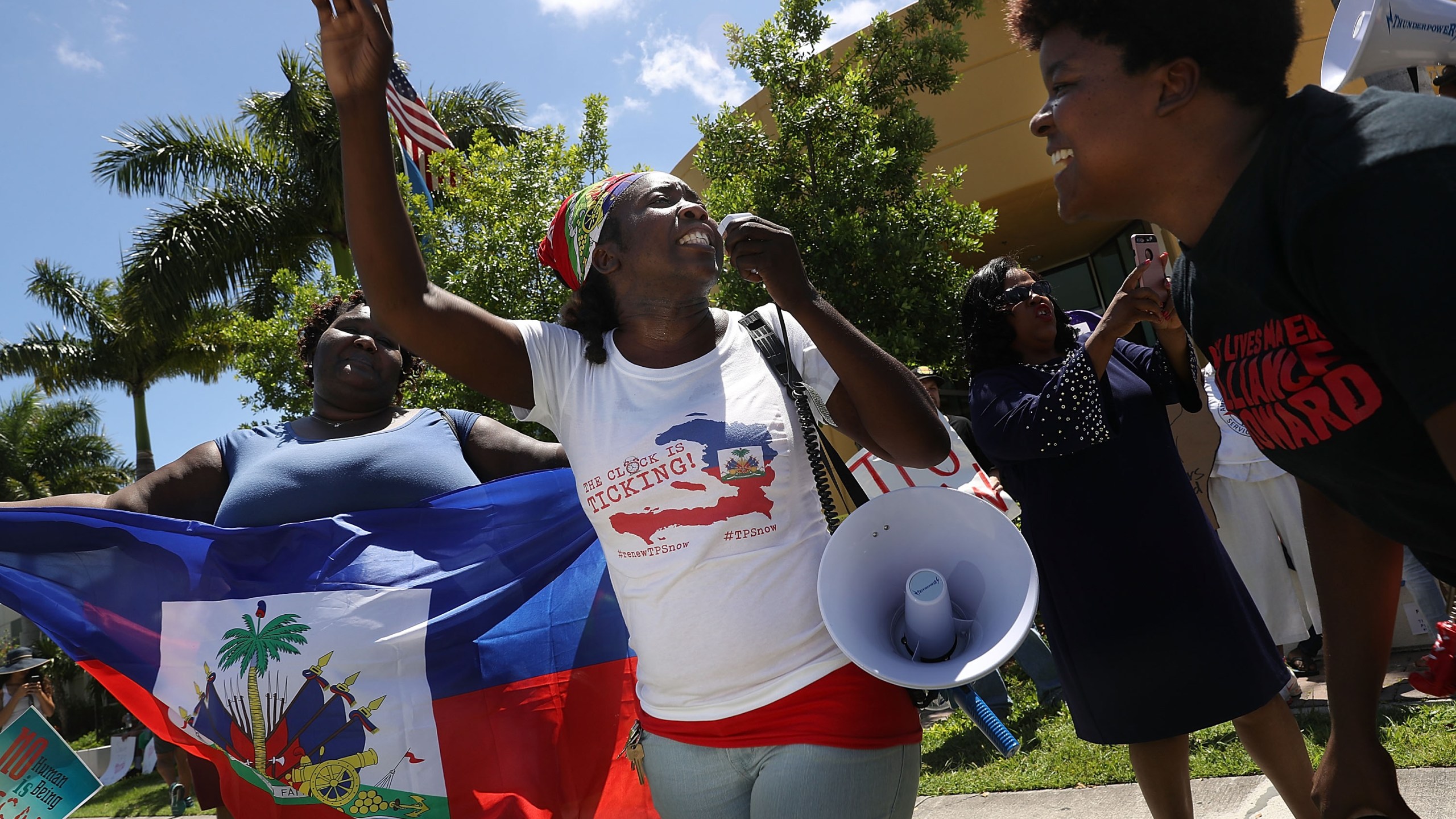 Santcha Etienne, center, and others protest in front of the United States Citizenship and Immigration Services office in Broward County to urge the Department of Homeland Security to extend Temporary Protected Status for Haitian immigrants on May 21, 2017, in Fort Lauderdale, Florida. (Credit: Joe Raedle/Getty Images)