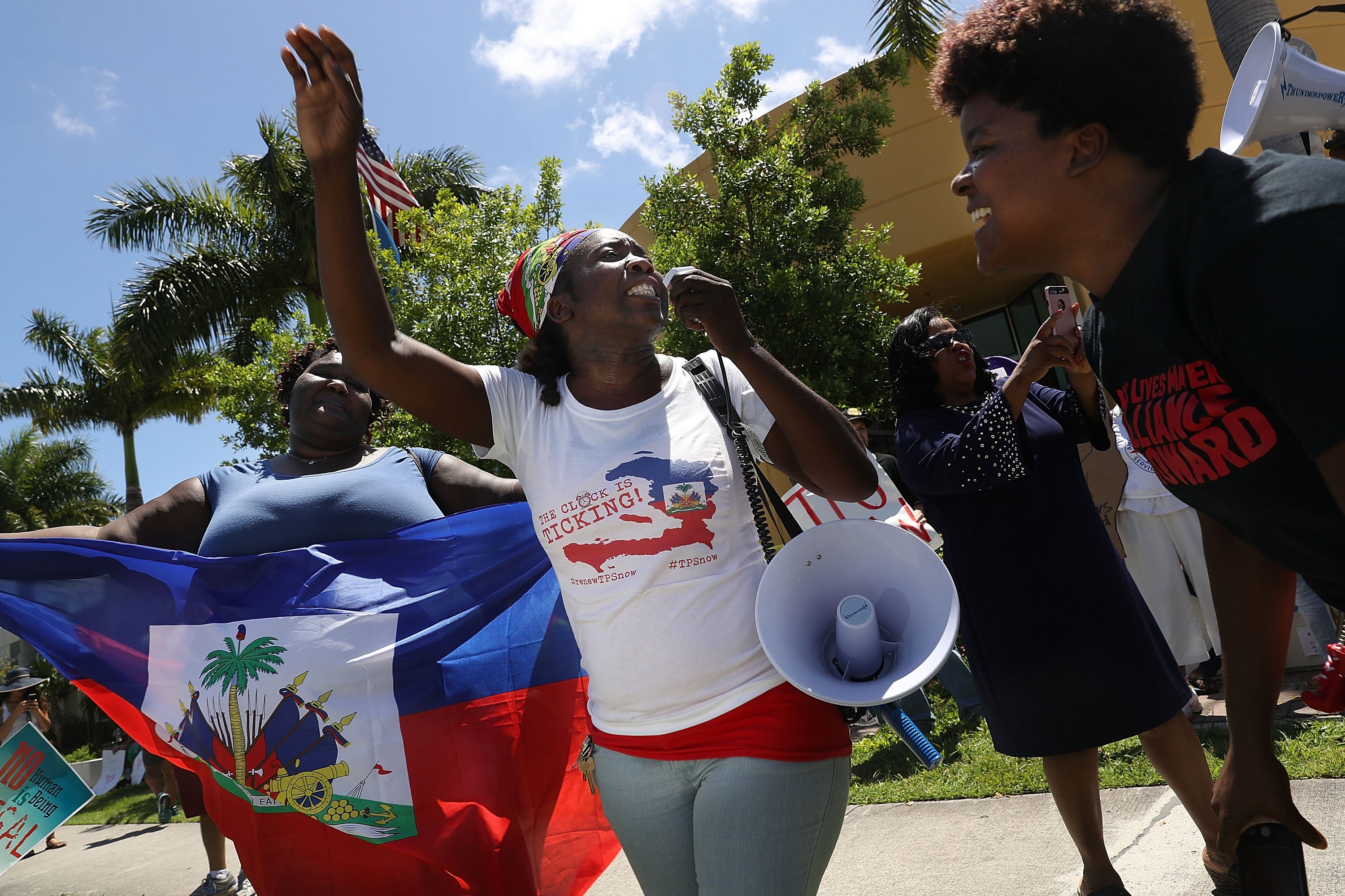 Santcha Etienne, center, and others protest in front of the United States Citizenship and Immigration Services office in Broward County to urge the Department of Homeland Security to extend Temporary Protected Status for Haitian immigrants on May 21, 2017, in Fort Lauderdale, Florida. (Credit: Joe Raedle/Getty Images)