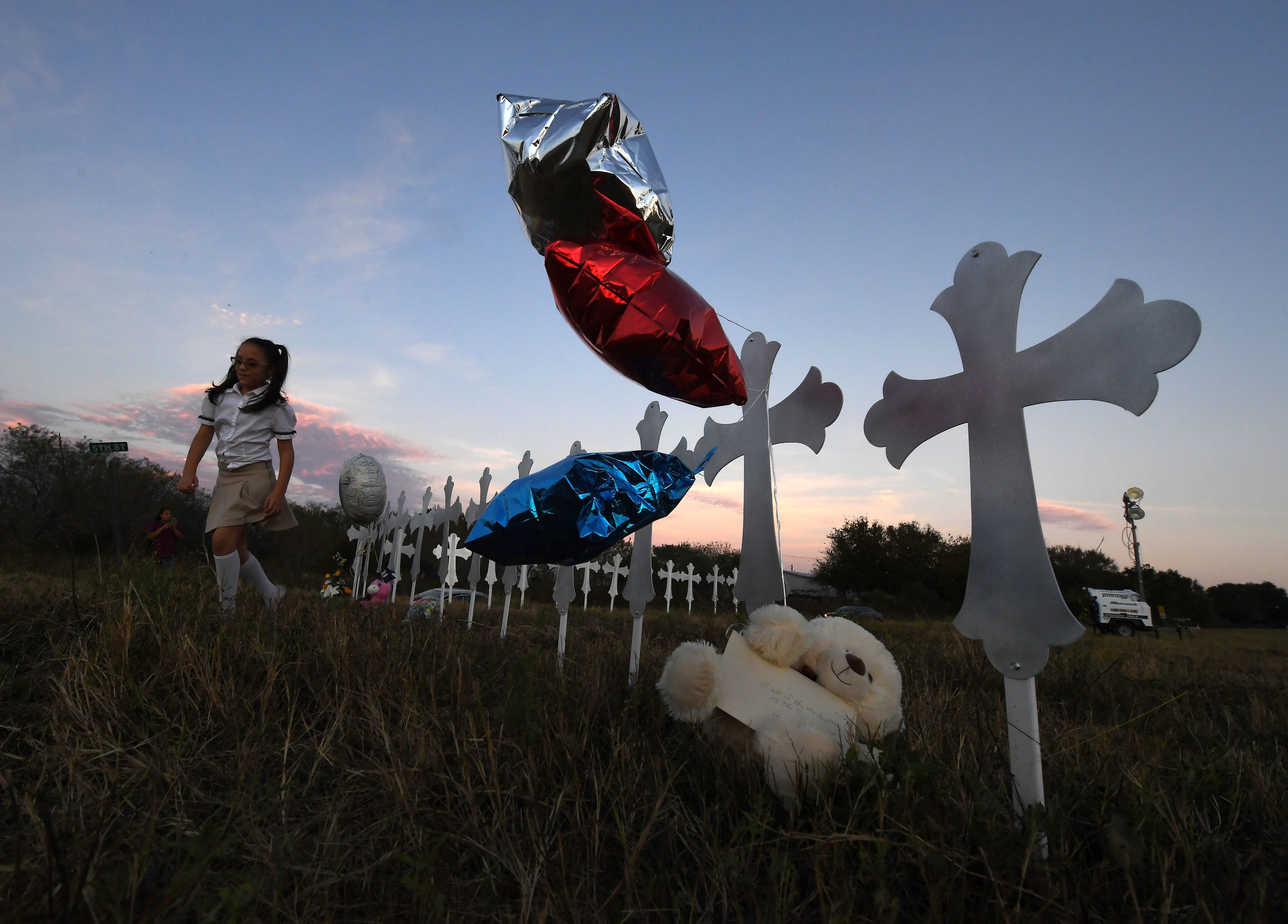 Heather Cooper, 8, leaves after placing her favorite doll on a row of crosses for each victim, after a mass shooting that killed 26 people in Sutherland Springs, Texas on November 6, 2017. (Credit: MARK RALSTON/AFP/Getty Images)