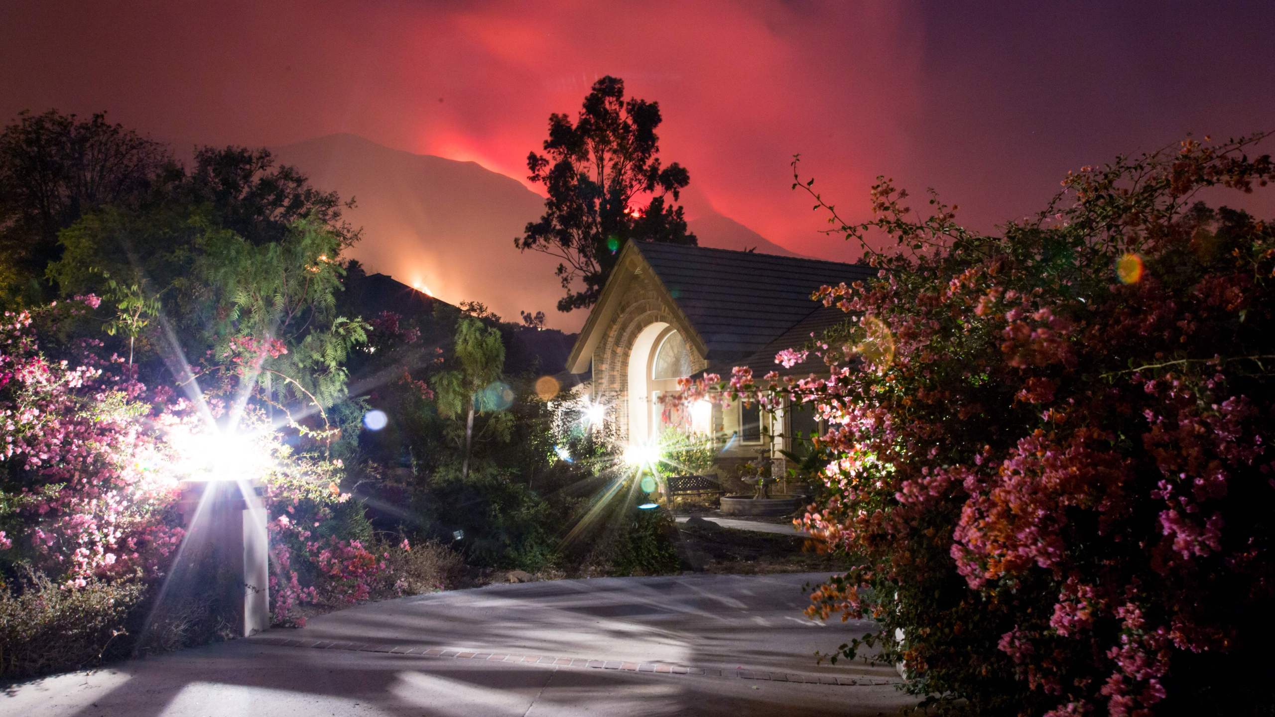 The Thomas Fire burns behind houses in Ojai on Dec. 7, 2017. (Credit: AFP PHOTO / Kyle Grillot)