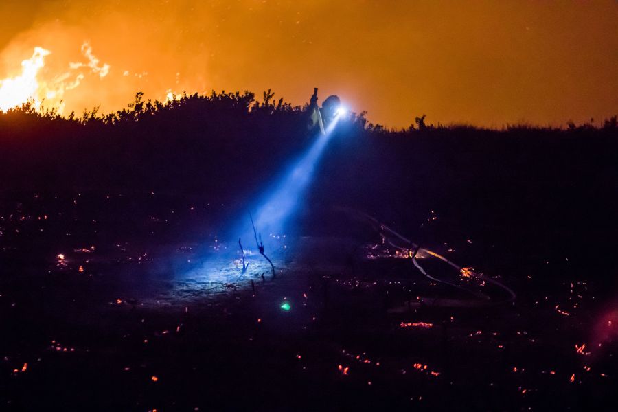 Firefighters work to extinguish the Thomas Fire as it burns past the 101 Highway towards the Pacific Coast Highway in Ventura Dec. 7, 2017. (Credit: KYLE GRILLOT/AFP/Getty Images)