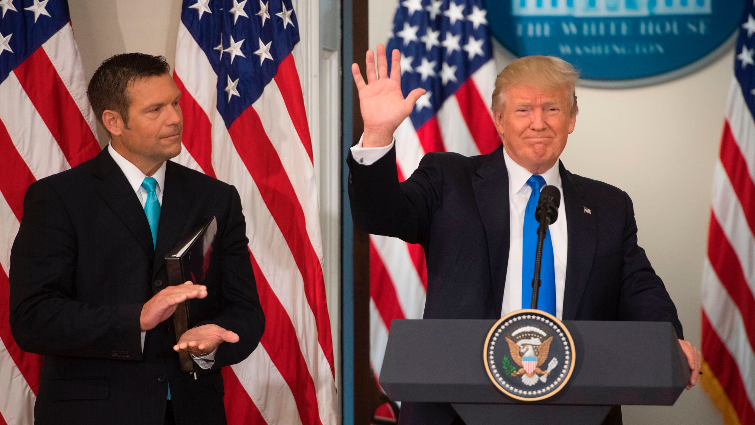 President Donald Trump waves after speaking alongside Kansas Secretary of State Kris Kobach, left, during the first meeting of the Presidential Advisory Commission on Election Integrity in the Eisenhower Executive Office Building next to the White House in Washington, D.C., July 19, 2017. (Credit: SAUL LOEB/AFP/Getty Images)