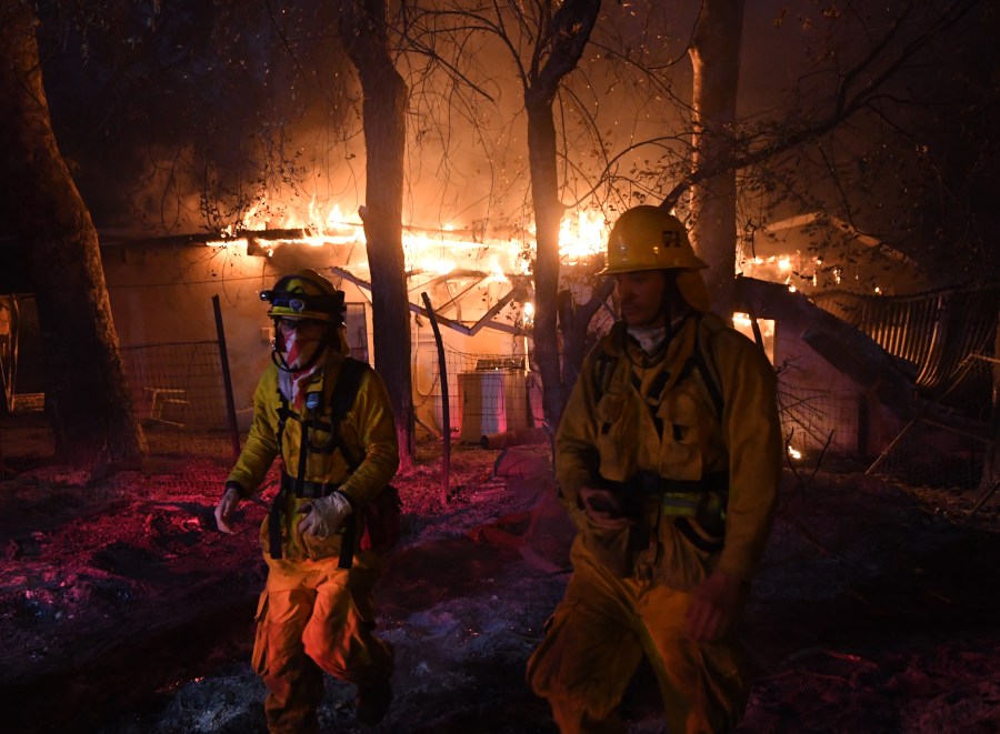 Firefighters move away from a burning house after discovering downed live power lines, as the Thomas wildfire continued to burn in Carpinteria, California, on Dec. 10, 2017. (Credit: Mark Ralston / AFP / Getty Images)