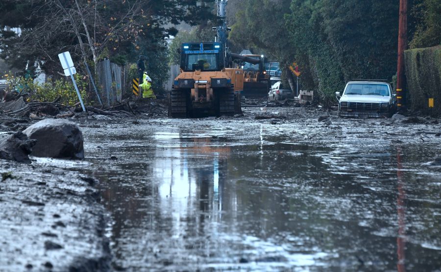 A car remains stuck in the mud as a cleanup crew work to clear mud beside a closed off section of US Hwy 101 in Montecito on January 9, 2018. (Credit: FREDERIC J. BROWN/AFP/Getty Images)