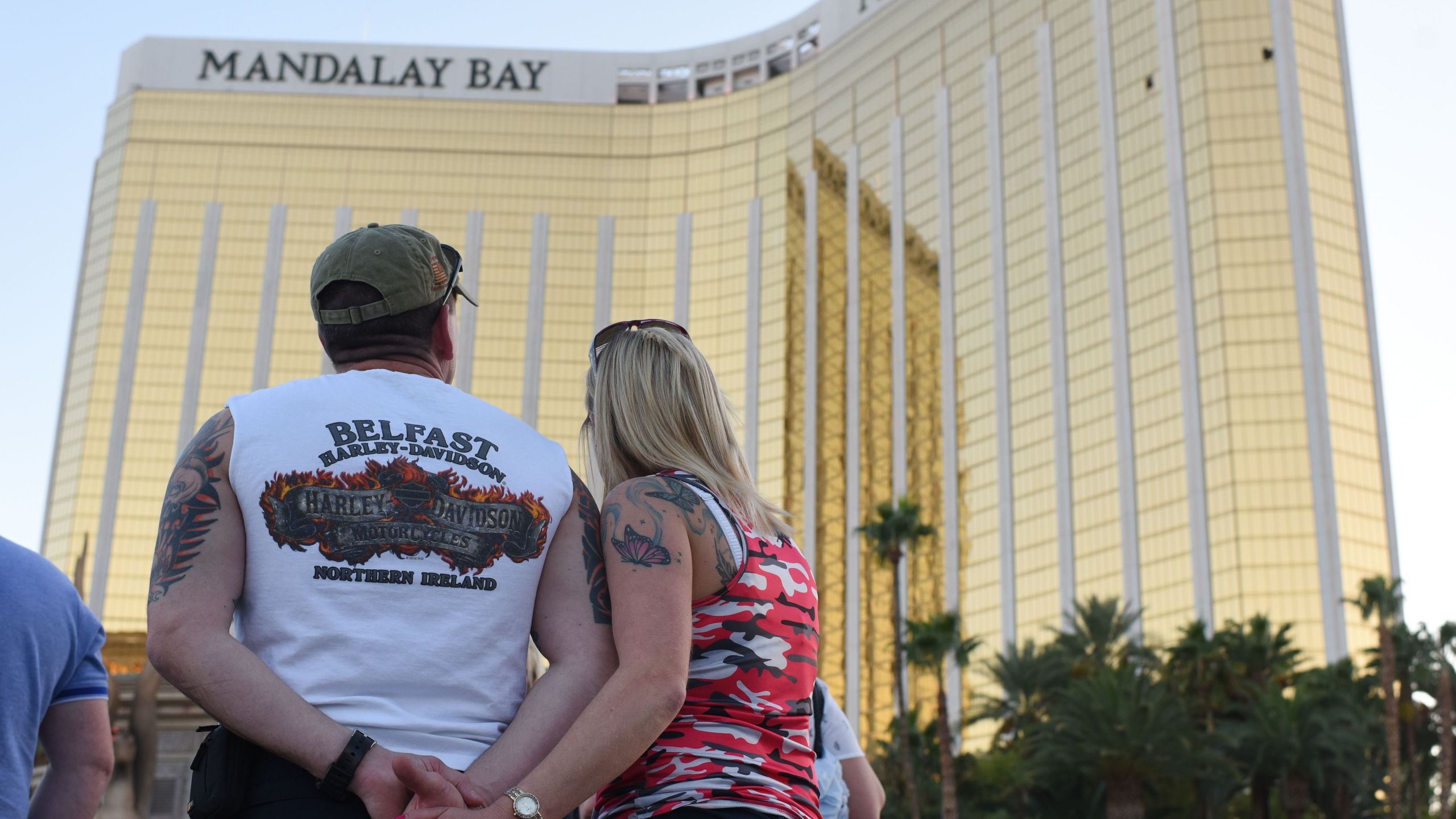 A couple stops on the Las Vegas Strip October 4, 2017, to look up at the two broken windows in the Mandalay Bay hotel from which killer Stephen Paddock let loose the worst mass shooting in modern American history. (Credit: ROBYN BECK/AFP/Getty Images)