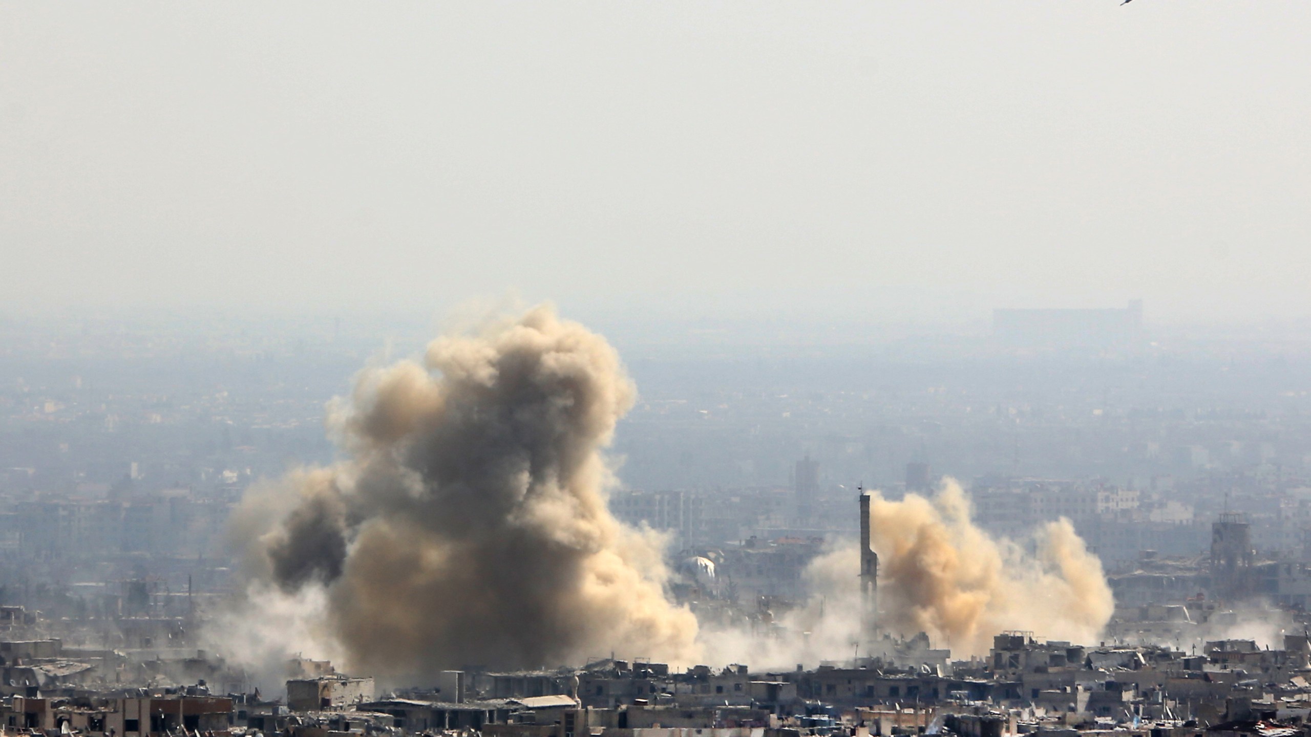 A picture taken from a government-controlled area on the outskirts of Harasta on the northeastern suburbs of Damascus on February 21, 2018, shows smoke rising from areas targeted by Syrian army shelling in the towns of Arbin and Harasta. (STRINGER/AFP/Getty Images)