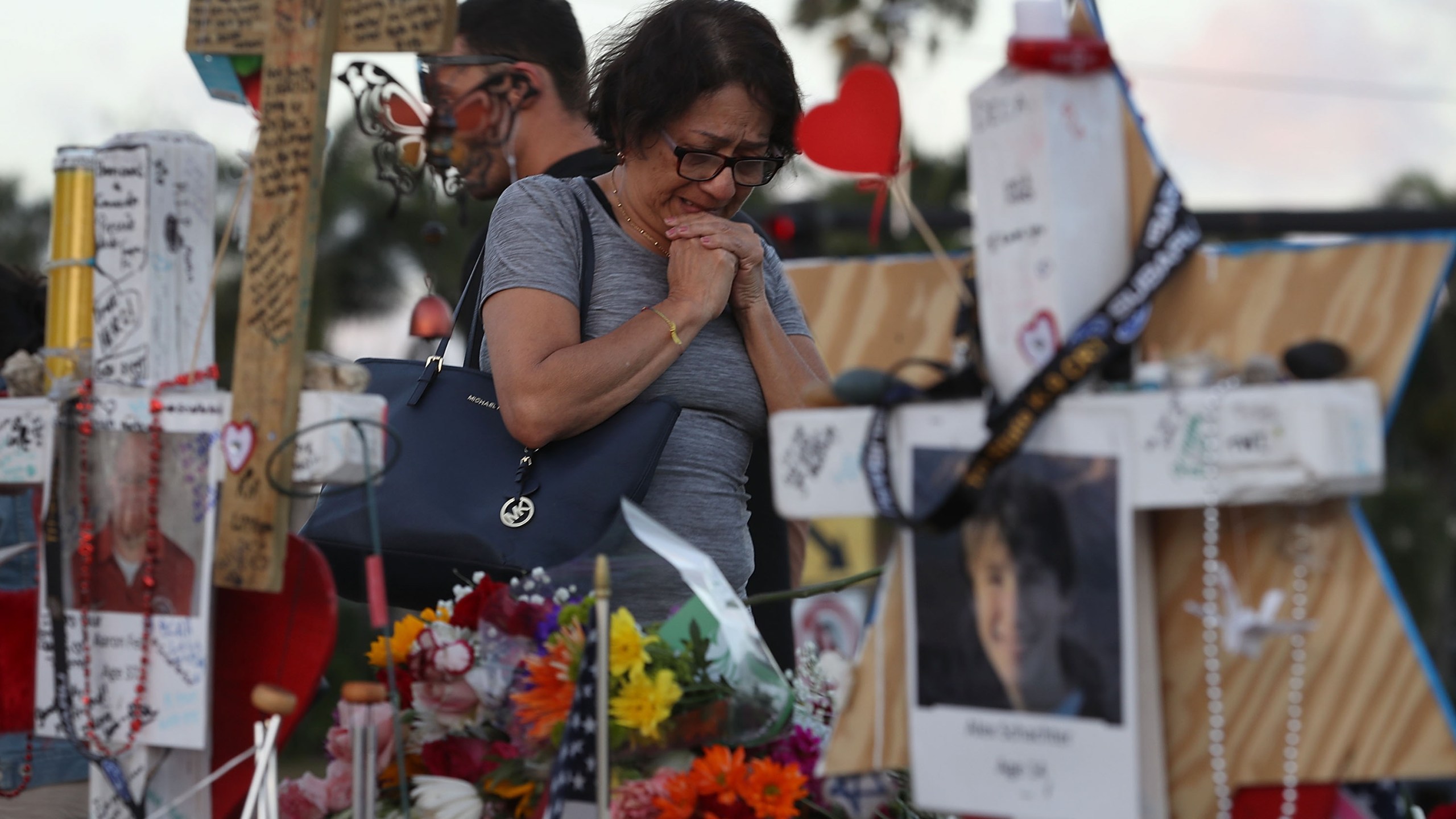 A woman cries as she visits a makeshift memorial setup in front of Marjory Stoneman Douglas High School in memory of the 17 people that were killed on February 14, on February 21, 2018 in Parkland, Florida. (Credit: Joe Raedle/Getty Images)