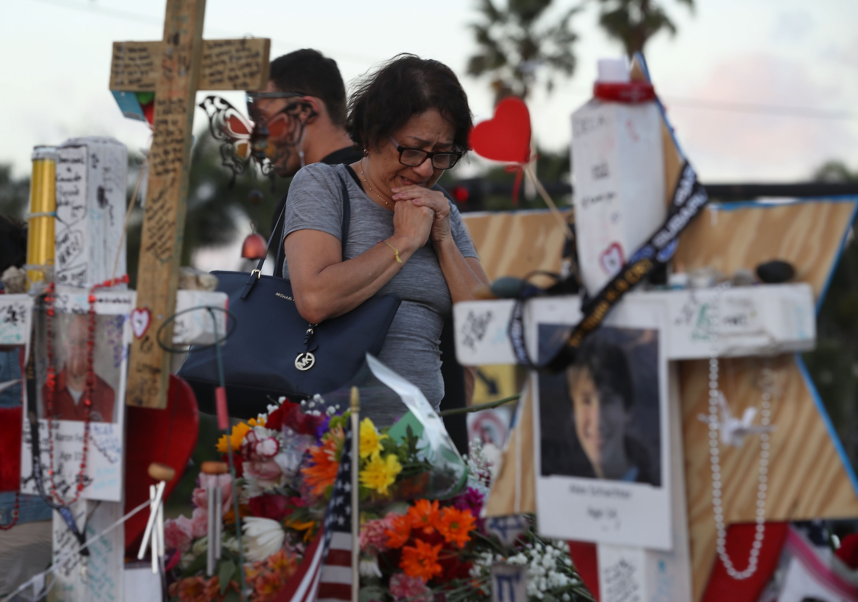 A woman cries as she visits a makeshift memorial setup in front of Marjory Stoneman Douglas High School in memory of the 17 people that were killed on February 14, on February 21, 2018 in Parkland, Florida. (Credit: Joe Raedle/Getty Images)