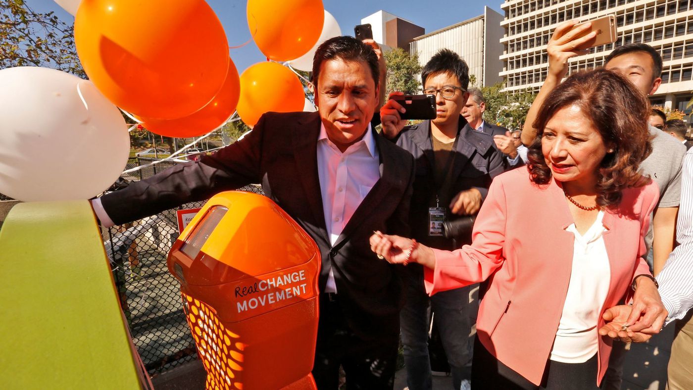 Los Angeles City Councilman Jose Huizar, left, and Los Angeles County Supervisor Hilda L. Solis put money into a homeless donation meter in downtown L.A.'s Grand Park on Feb. 8, 2018. (Credit: Al Seib / Los Angeles Times)