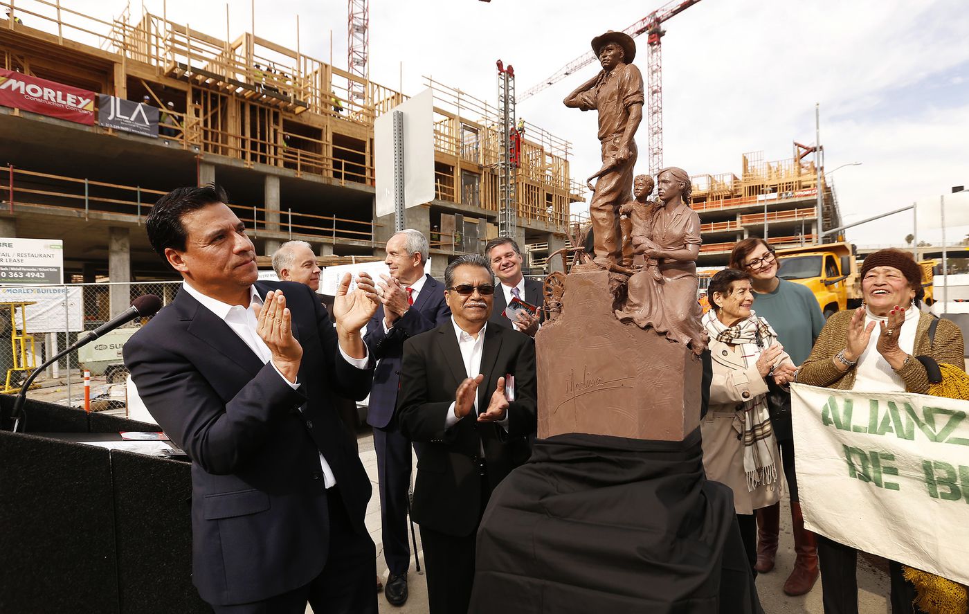 Los Angeles City Councilman Jose Huizar, left, applauds the unveiling of a scale model of a 19-foot monument depicting a "bracero" guest worker on March 8, 2018. (Credit: Al Seib / Los Angeles Times)