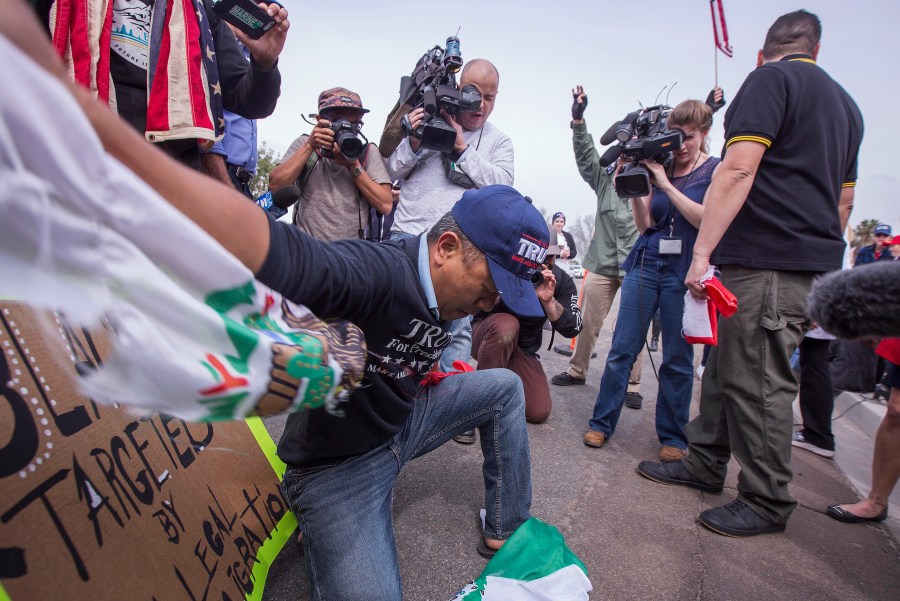 A man tears up a Mexican flag that was taken from a counter protester as supporters of President Donald Trump rally for the president during his visit to see the controversial border wall prototypes on March 13, 2018. (Credit: David McNew / Getty Images)