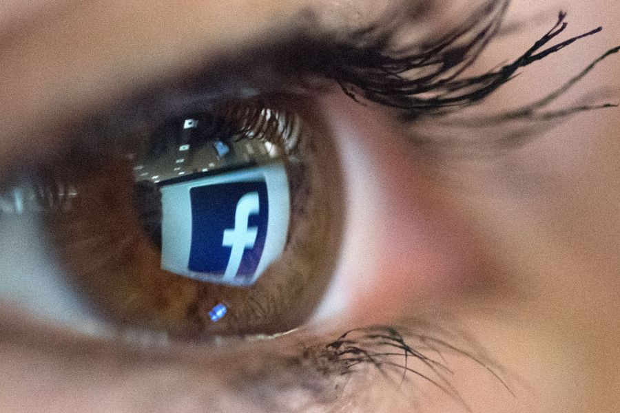 An illustration picture taken on March 22, 2018, in Paris shows a close-up of the Facebook logo in the eye of an AFP staff member posing while she looks at a flipped logo of Facebook. (Credit: Christophe Simon / AFP / Getty Images)