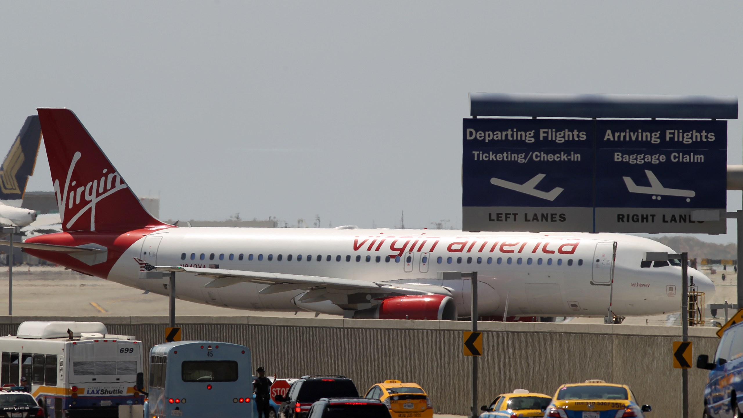 A Virgin America jet taxis into take-off position as cars enter the Los Angles International Airport on April 22, 2013. (Credit: David McNew/Getty Images)