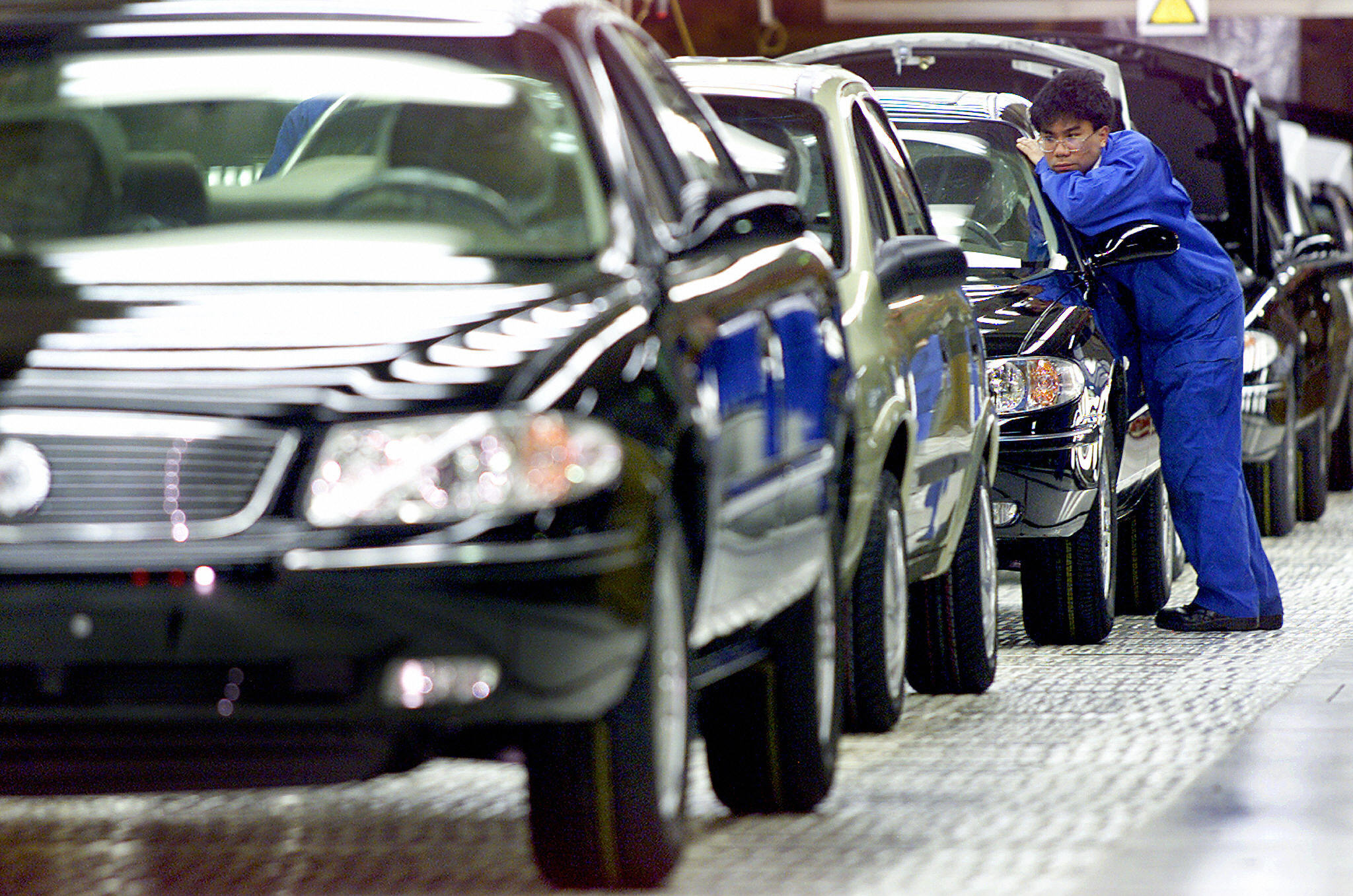 This file photo shows a worker looking at a side mirror of a car at the assembly line of General Motors Company in Shanghai. (Credit: LIU JIN/AFP/Getty Images)