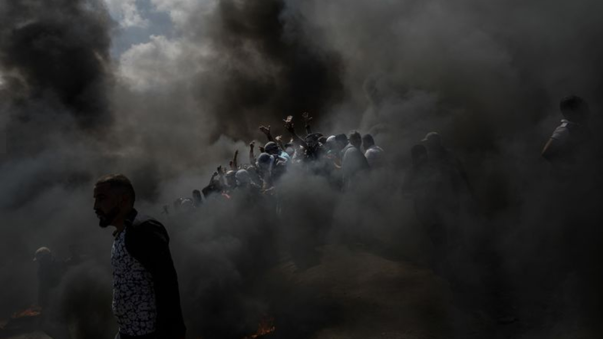 Palestinians cheer as they burn tires at the fence separating Israel and Gaza in a camp east of Gaza City on May 15,2018. (Credit: Marcus Yam / Los Angeles Times)