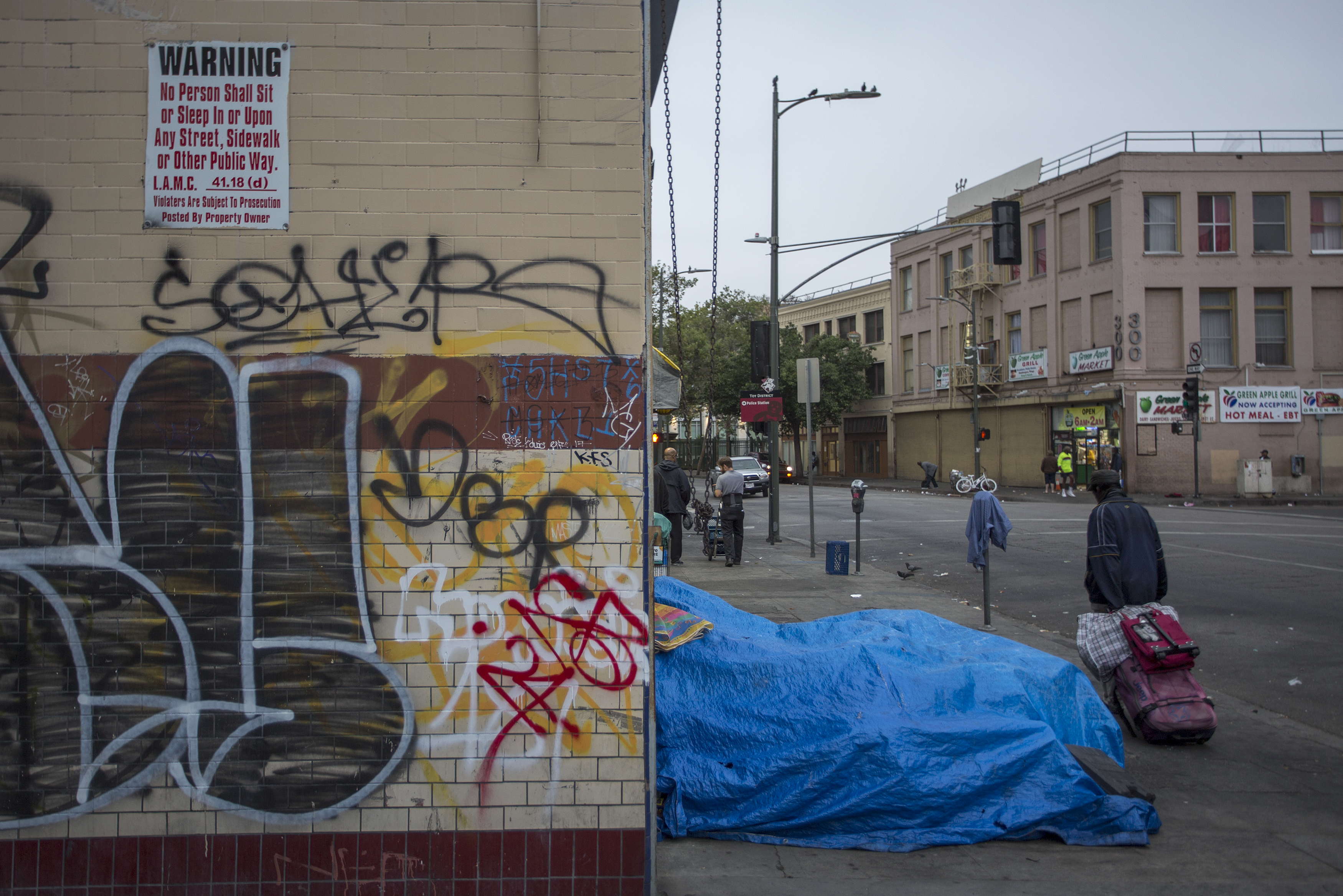 Homeless people camp on a sidewalk on Skid Row near an old sign prohibiting them from being on the sidewalk on May 1, 2017 in Los Angeles. (Credit: David McNew/Getty Images)