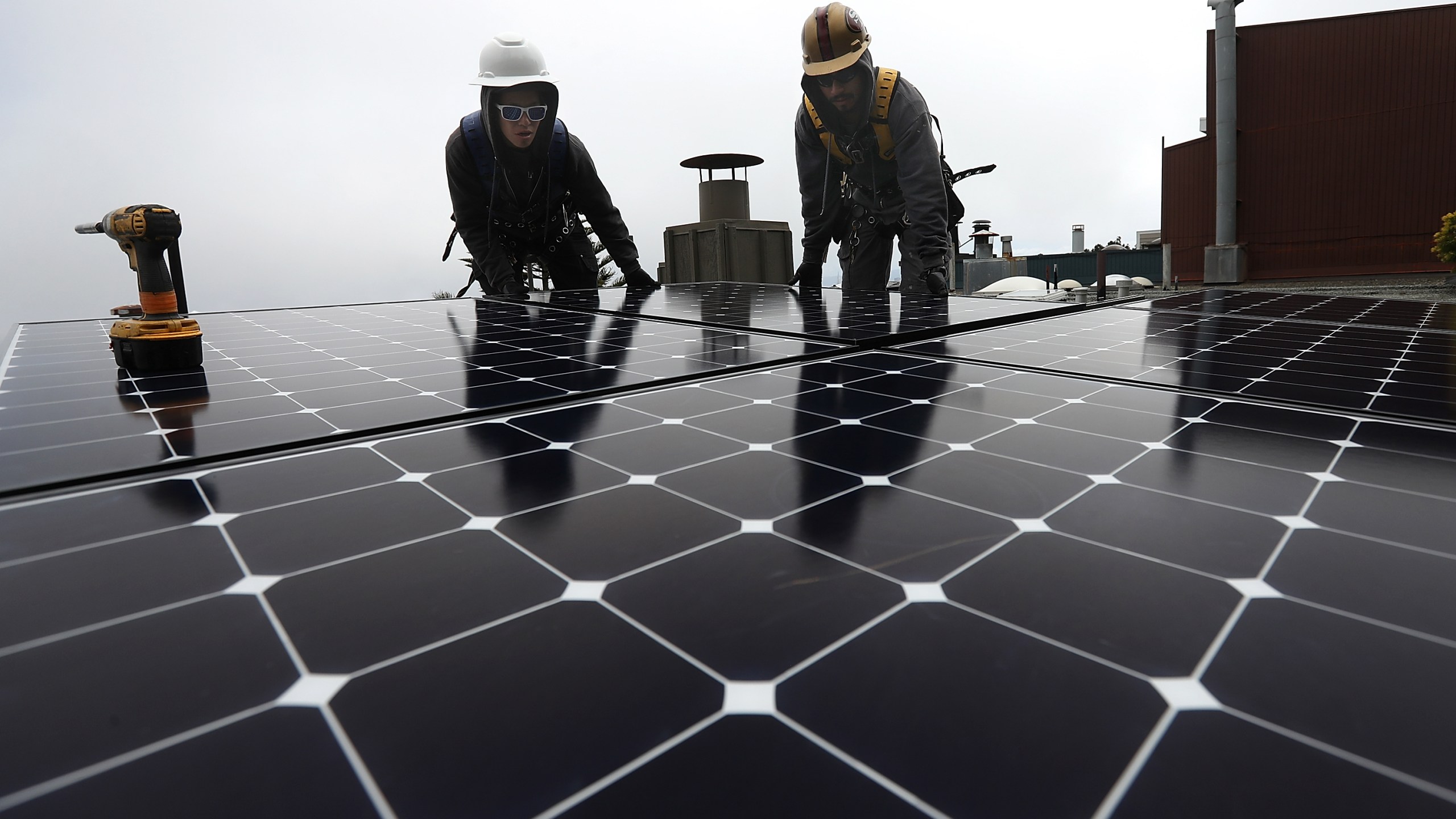 Luminalt solar installers Pam Quan, left, and Walter Morales, right, install solar panels on the roof of a home on May 9, 2018, in San Francisco. (Credit: Justin Sullivan / Getty Images)