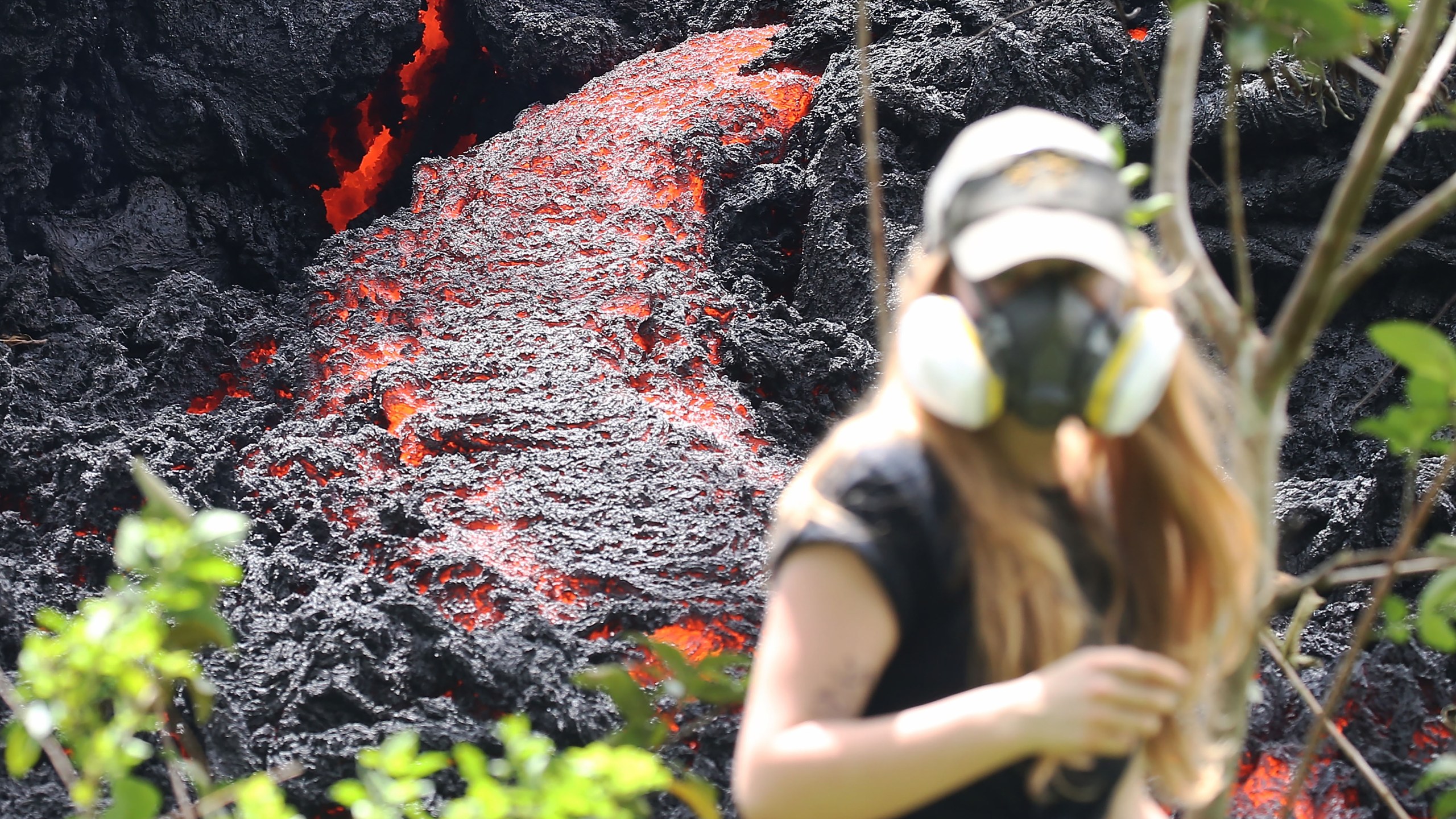 Lava flows at a new fissure in the aftermath of eruptions from the Kilauea volcano on Hawaii's Big Island as a local resident walks nearby after taking photos on May 12, 2018 in Pahoa, Hawaii. (Credit: Mario Tama/Getty Images)