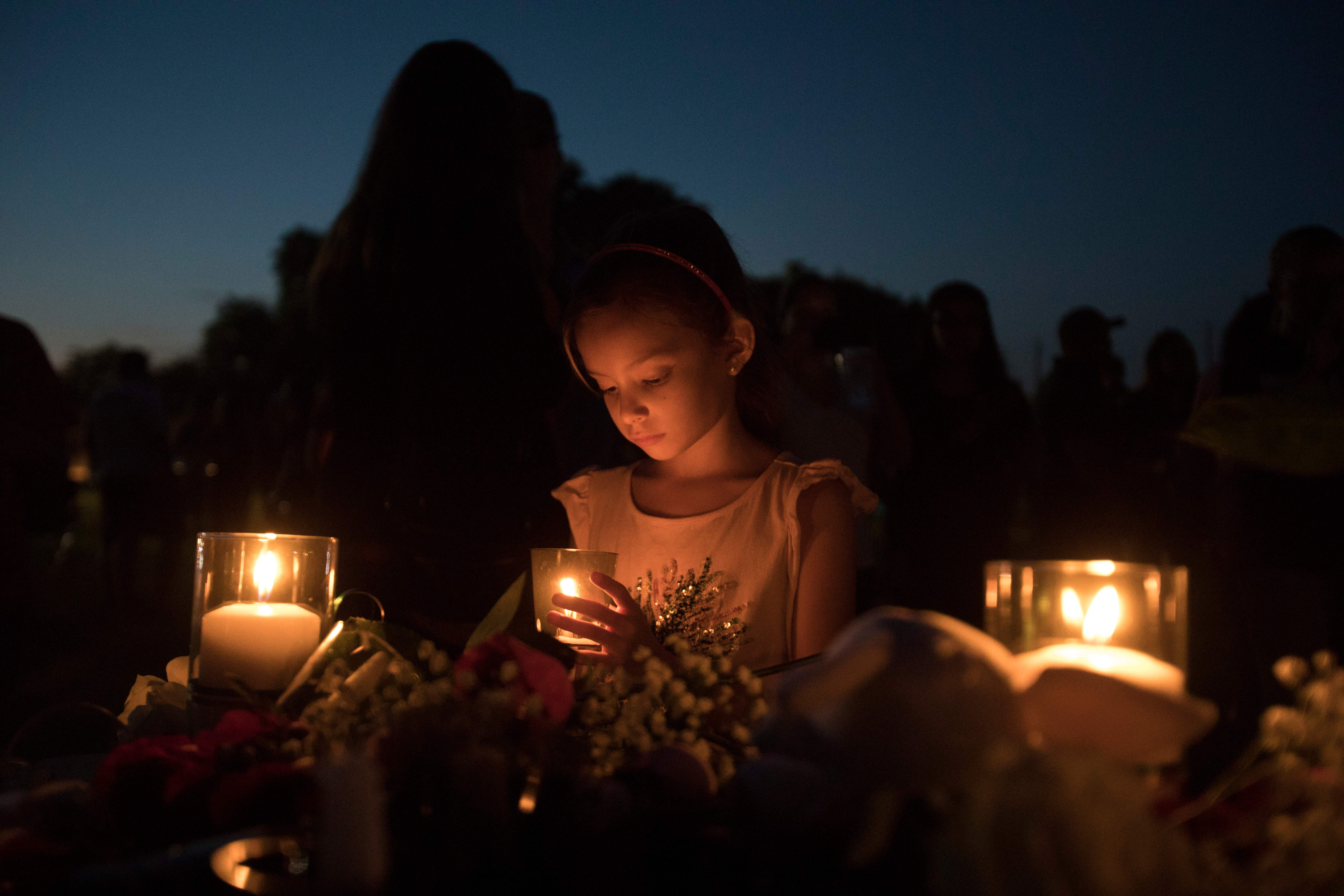 Lucretia Martinez, 7, stands before various momentos people have left during a candlelight vigil in Santa Fe, Texas, for the victims of the mass shooting on May 18, 2018. (Credit: AFP / Getty Images)