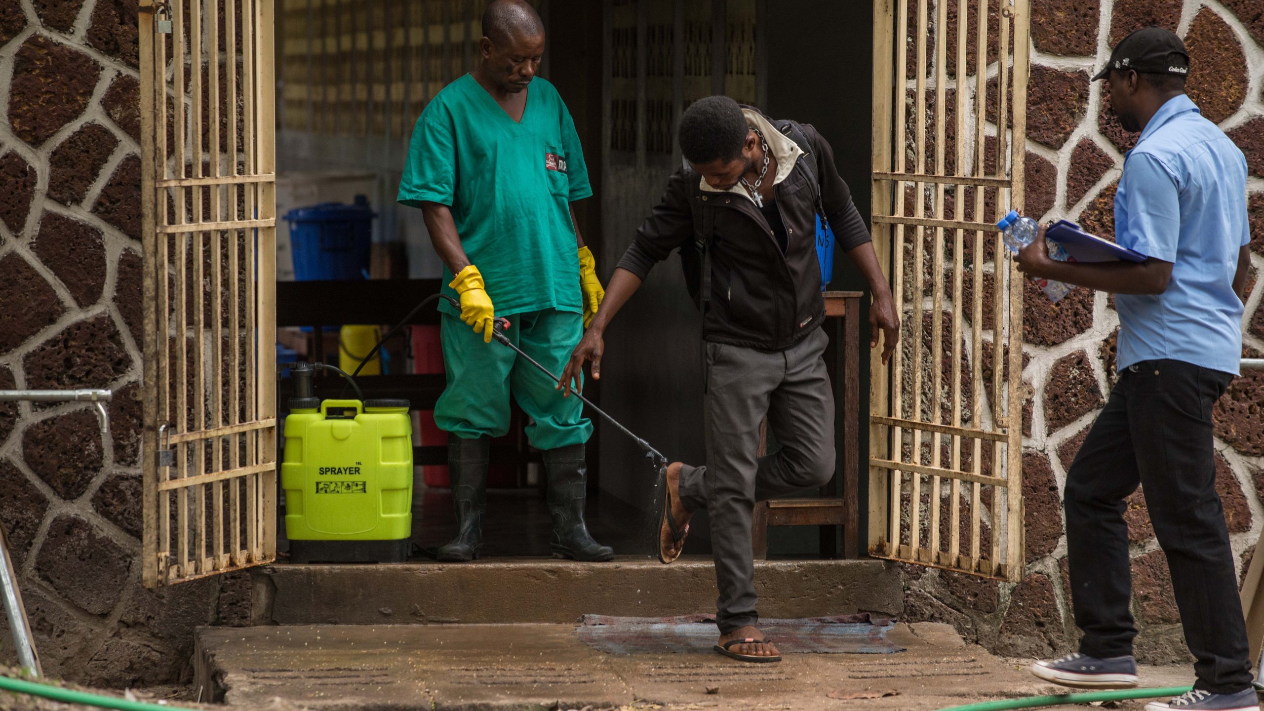 An attendant charged to handle the access to the Ebola security zone disinfects shoes outside the Wangata Reference Hospital in Mbandaka, northwest of DR Congo on May 20, 2018. (Credit: Junior Kannah/AFP/Getty Images)