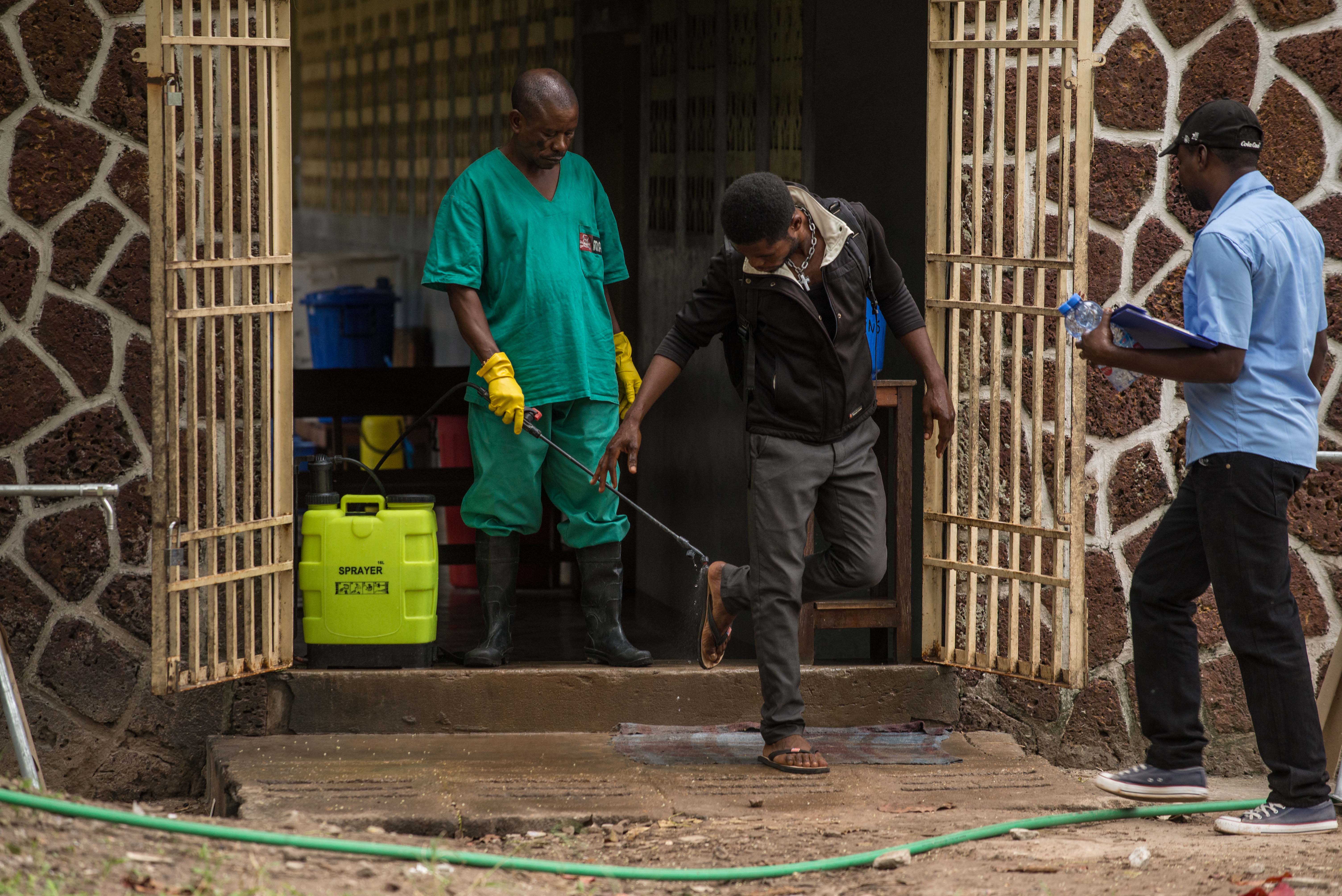 An attendant charged to handle the access to the Ebola security zone disinfects shoes outside the Wangata Reference Hospital in Mbandaka, northwest of DR Congo on May 20, 2018. (Credit: Junior Kannah/AFP/Getty Images)