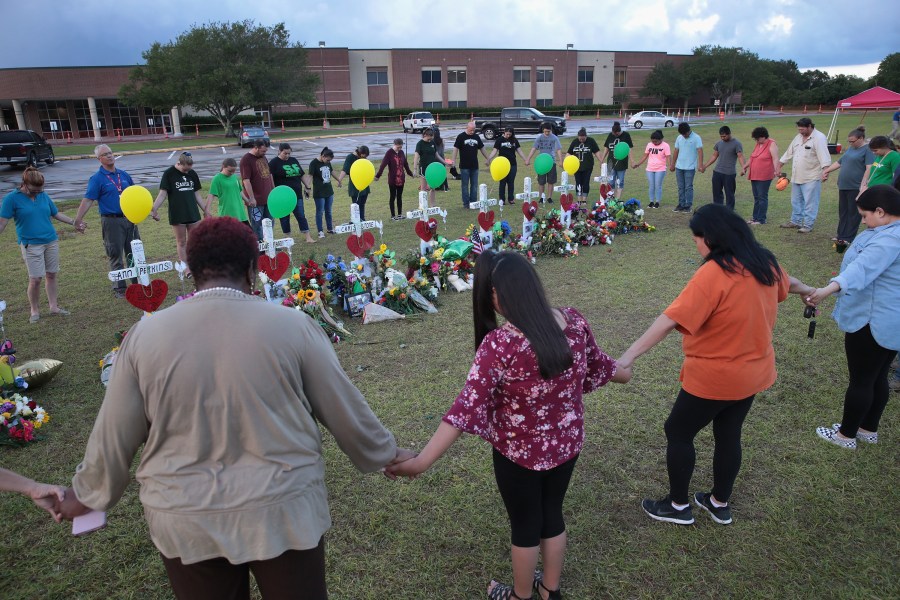 Mourners pray around a memorial in front of Santa Fe High School on May 21, 2018 in Santa Fe, Texas. (Credit: Scott Olson/Getty Images)