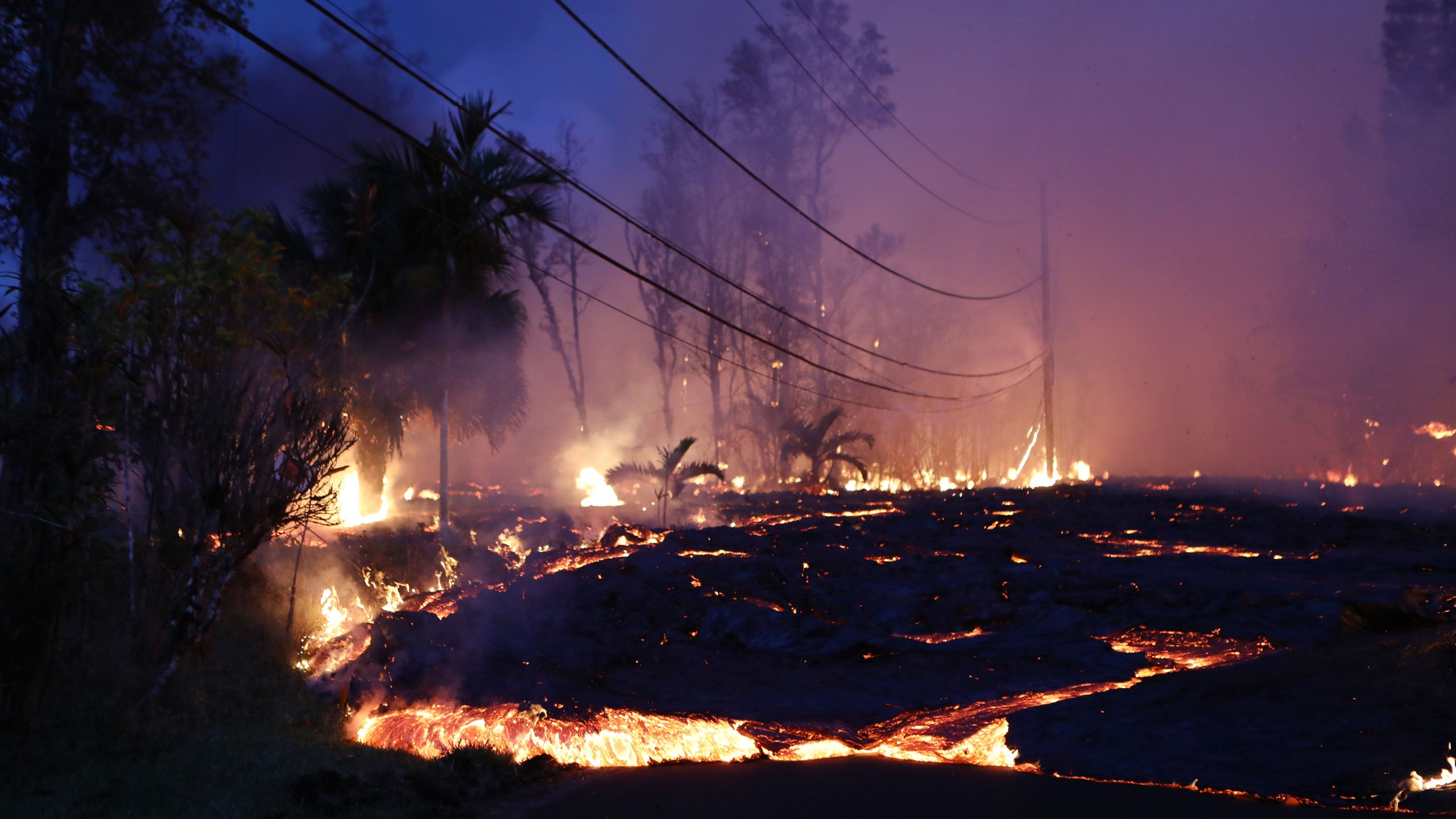 Lava from a Kilauea volcano fissure advances up a residential street in Leilani Estates, on Hawaii's Big Island, on May 27, 2018. (Credit: Mario Tama/Getty Images)