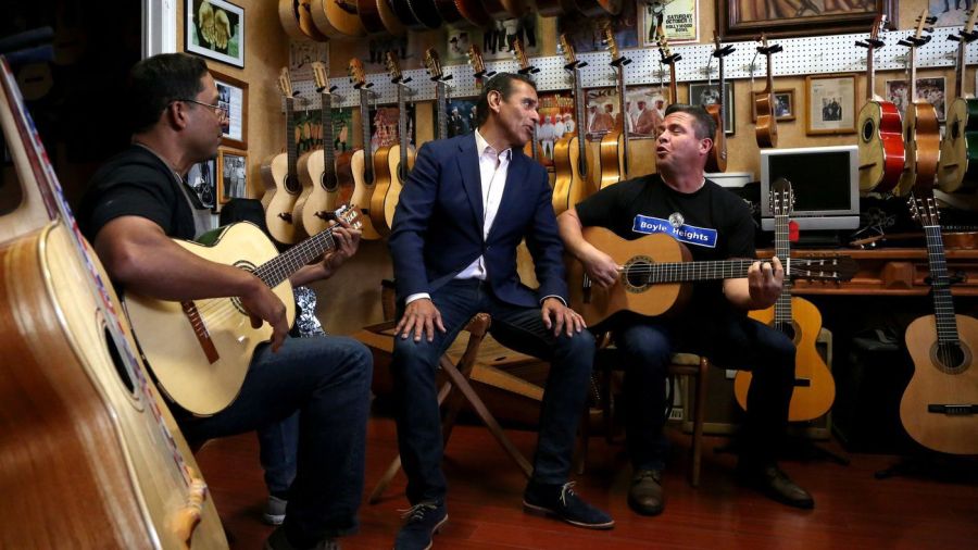 Antonio Villaraigosa, center, sings with Tomas Delgado, left, the owner of Candelas Guitars, and George Magallanes, as he campaigns for governor in Boyle Heights in late May 2018, just ahead of the June 5 election. (Credit: Katie Falkenberg / Los Angeles Times)