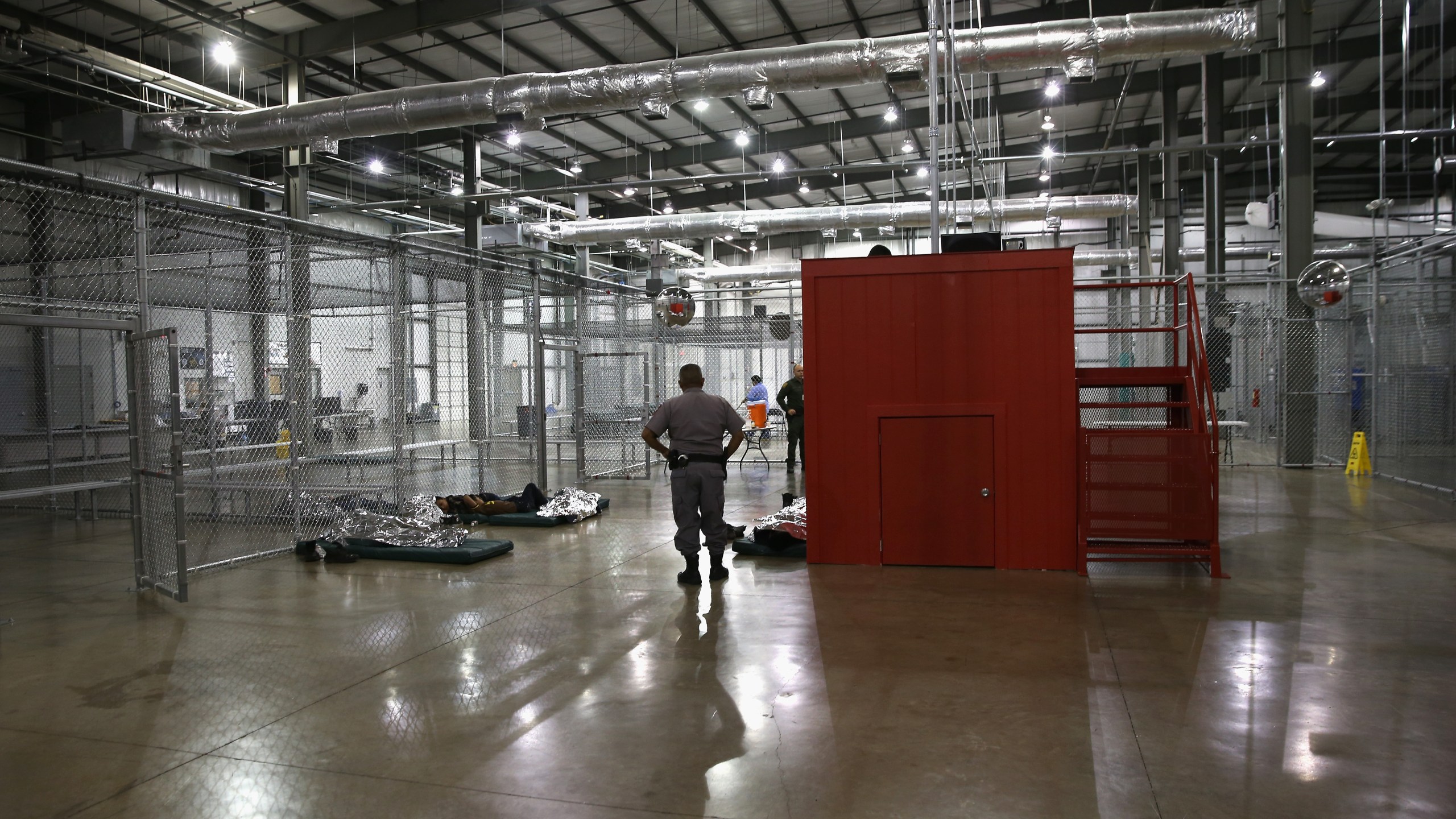 A security guard watches over unaccompanied minors at an immigration detention facility run by the U.S. Border Patrol on Sept. 8, 2014, in McAllen, Texas. (Credit: John Moore/Getty Images)