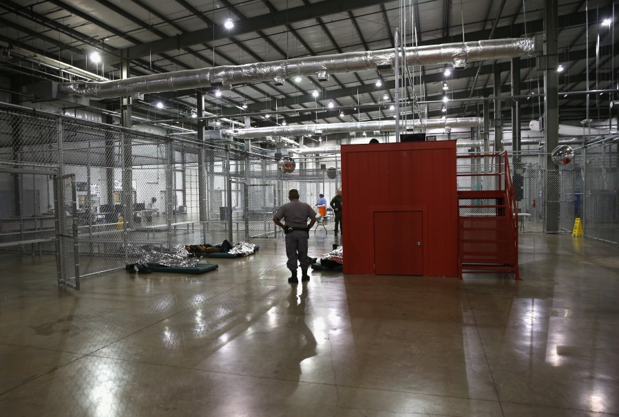 A security guard watches over unaccompanied minors at an immigration detention facility run by the U.S. Border Patrol on Sept. 8, 2014, in McAllen, Texas. (Credit: John Moore/Getty Images)