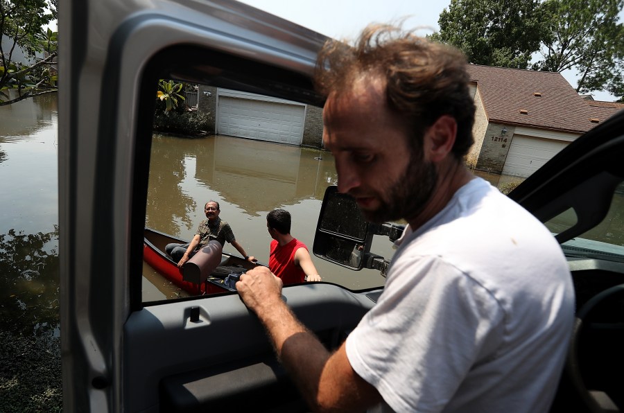 Chris Ginter (right) talks to residents on a boat in a flooded neighborhood on Sept. 6, 2017 in Houston. (Credit: Justin Sullivan/Getty Images)