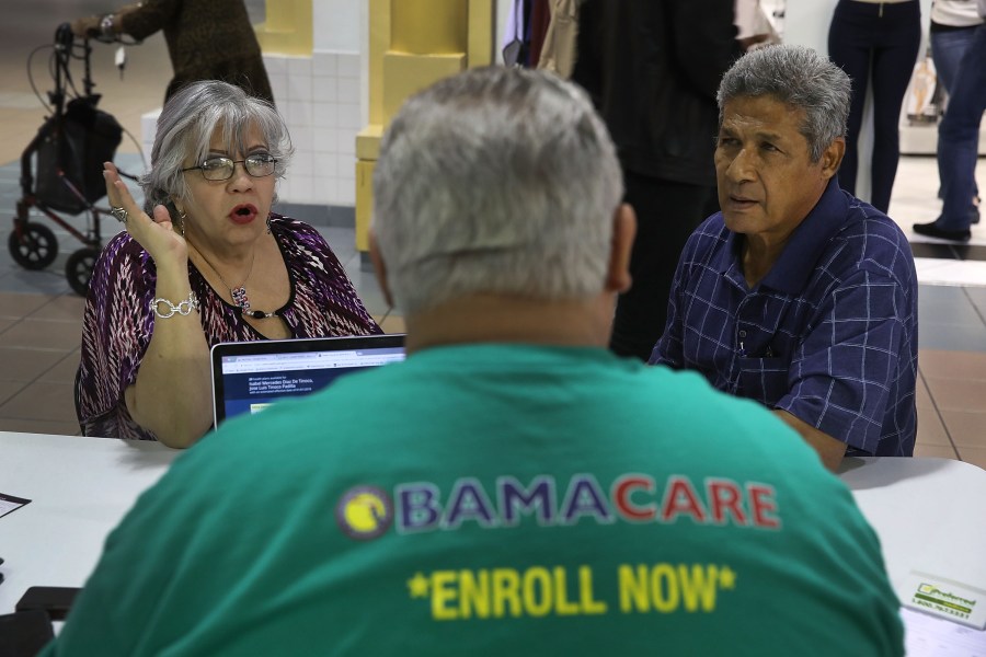 Isabel Diaz Tinoco, left, and Jose Luis Tinoco speak with Otto Hernandez, an insurance agent from Sunshine Life and Health Advisors, as they shop for insurance under the Affordable Care Act at a store setup in the Mall of Americas on Nov. 1, 2017, in Miami, Florida. (Credit: Joe Raedle/Getty Images)