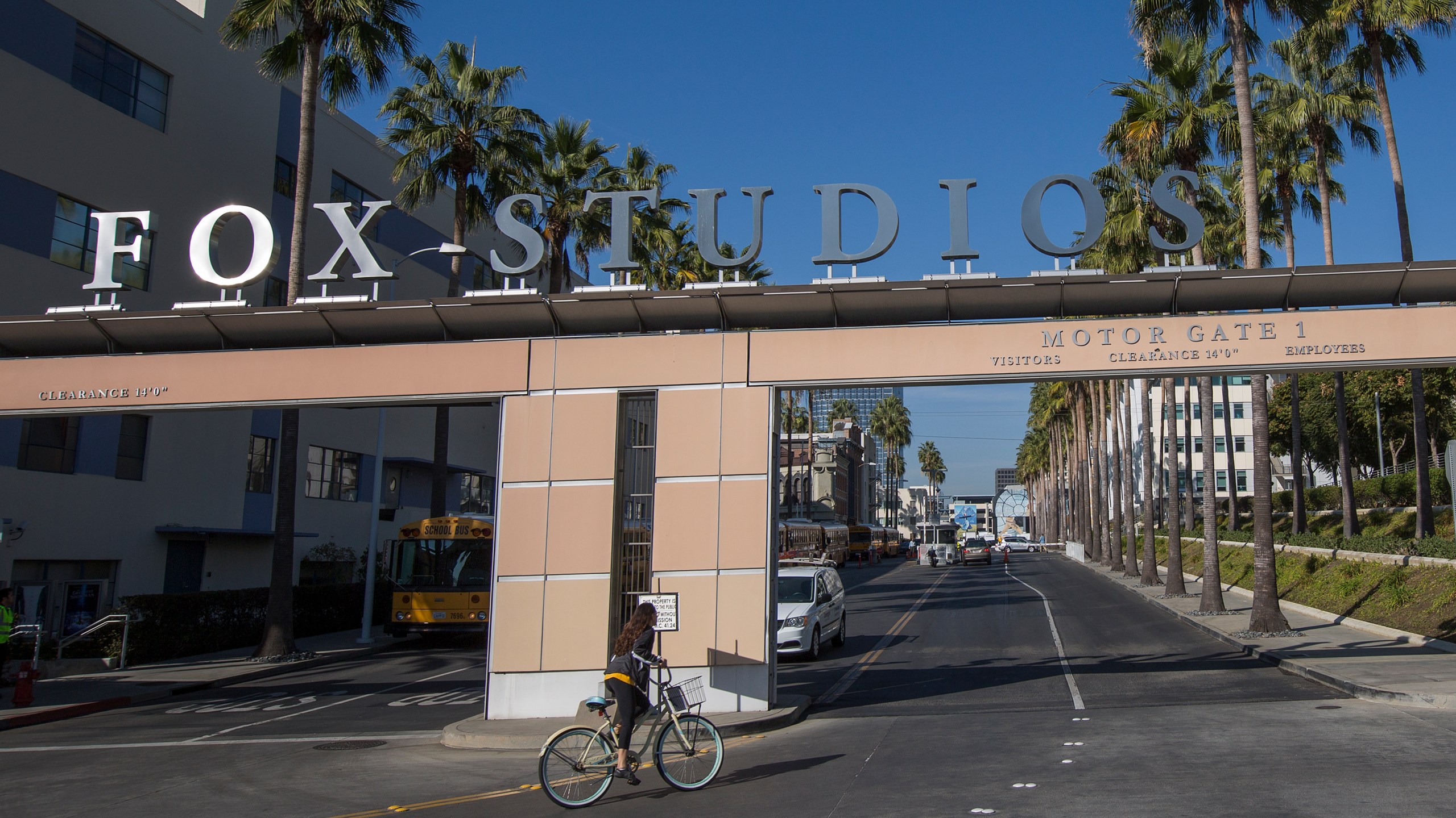 A bicyclist rides through the main entrance to Fox Studios after the Walt Disney Co. announced that it will acquire 21st Century Fox on Dec. 14, 2017, in Los Angeles (Credit: David McNew/Getty Images)