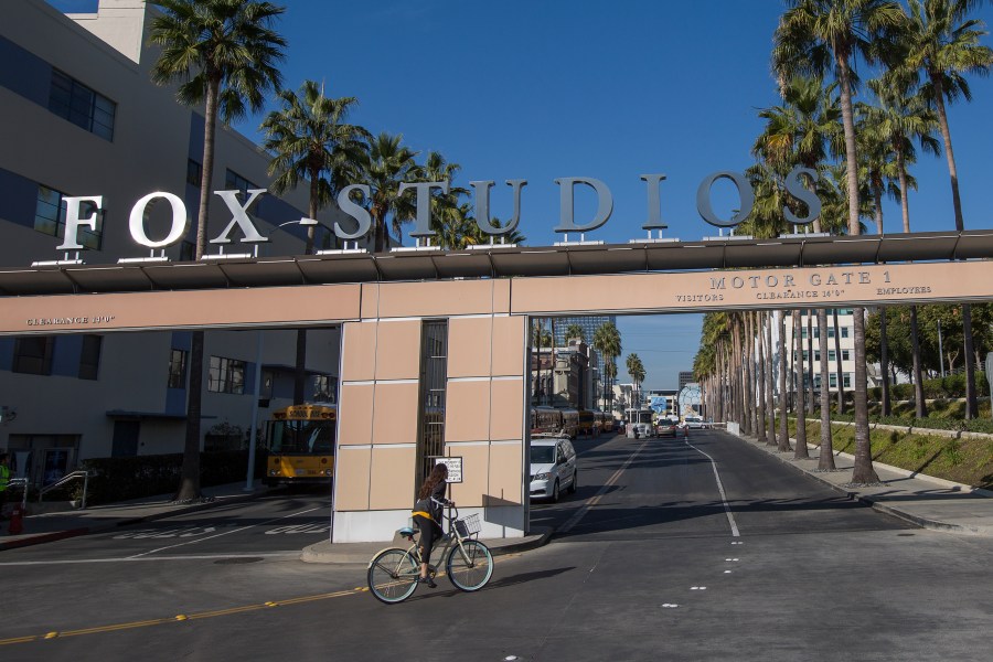 A bicyclist rides through the main entrance to Fox Studios after the Walt Disney Co. announced that it will acquire 21st Century Fox on Dec. 14, 2017, in Los Angeles (Credit: David McNew/Getty Images)