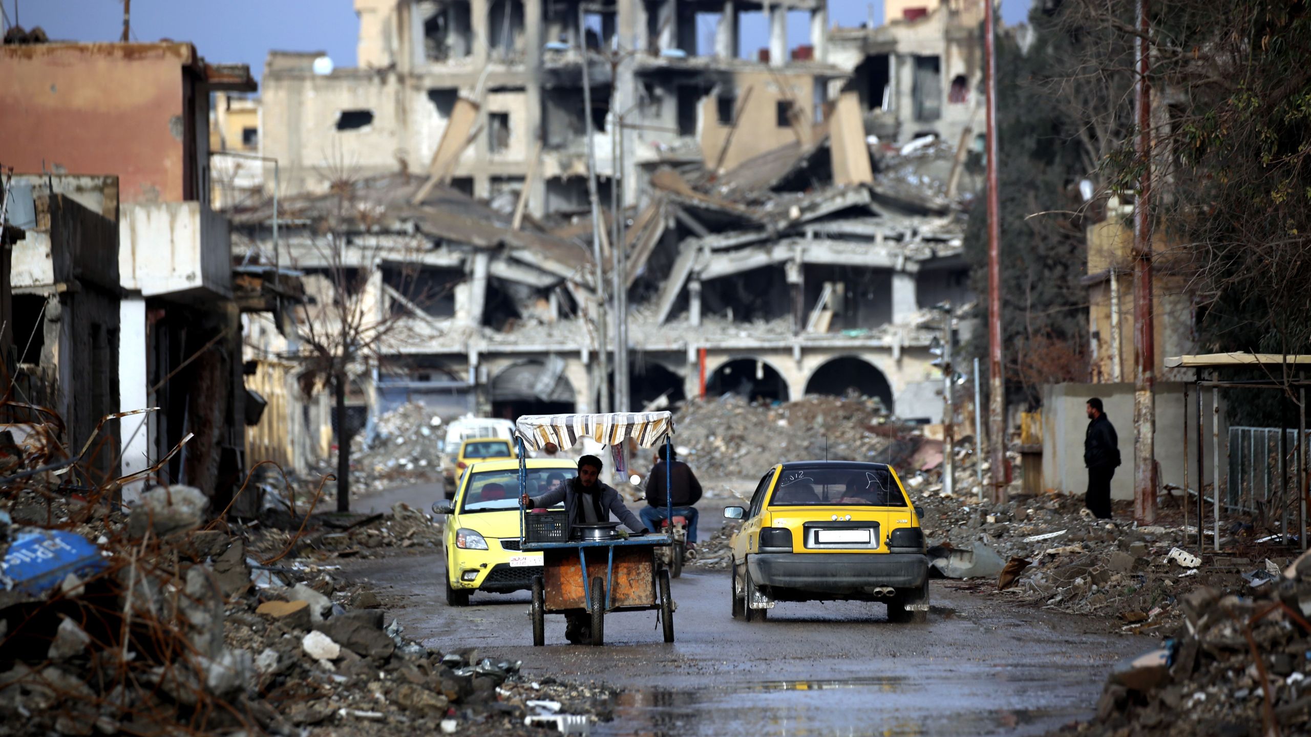 Syrians are shown traveling along a destroyed street in Raqqa on February 18, 2018. (Credit: Delil Souleiman/AFP/Getty Images)