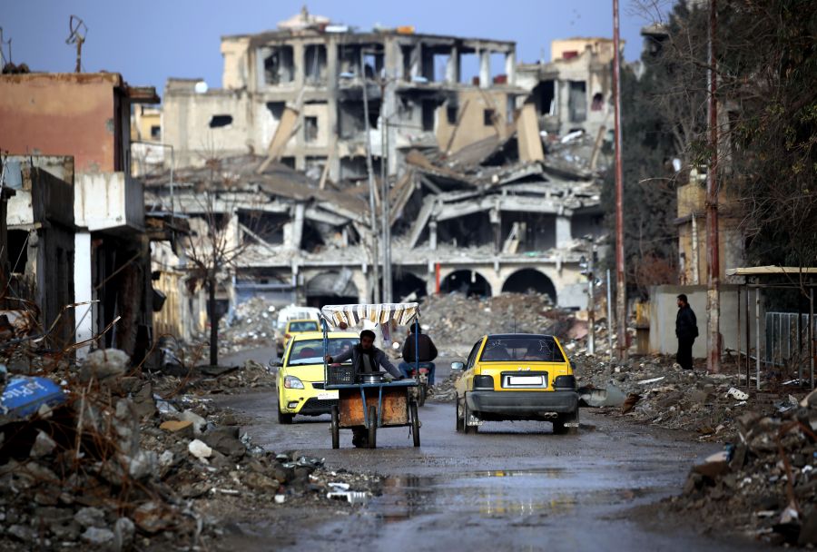 Syrians are shown traveling along a destroyed street in Raqqa on February 18, 2018. (Credit: Delil Souleiman/AFP/Getty Images)